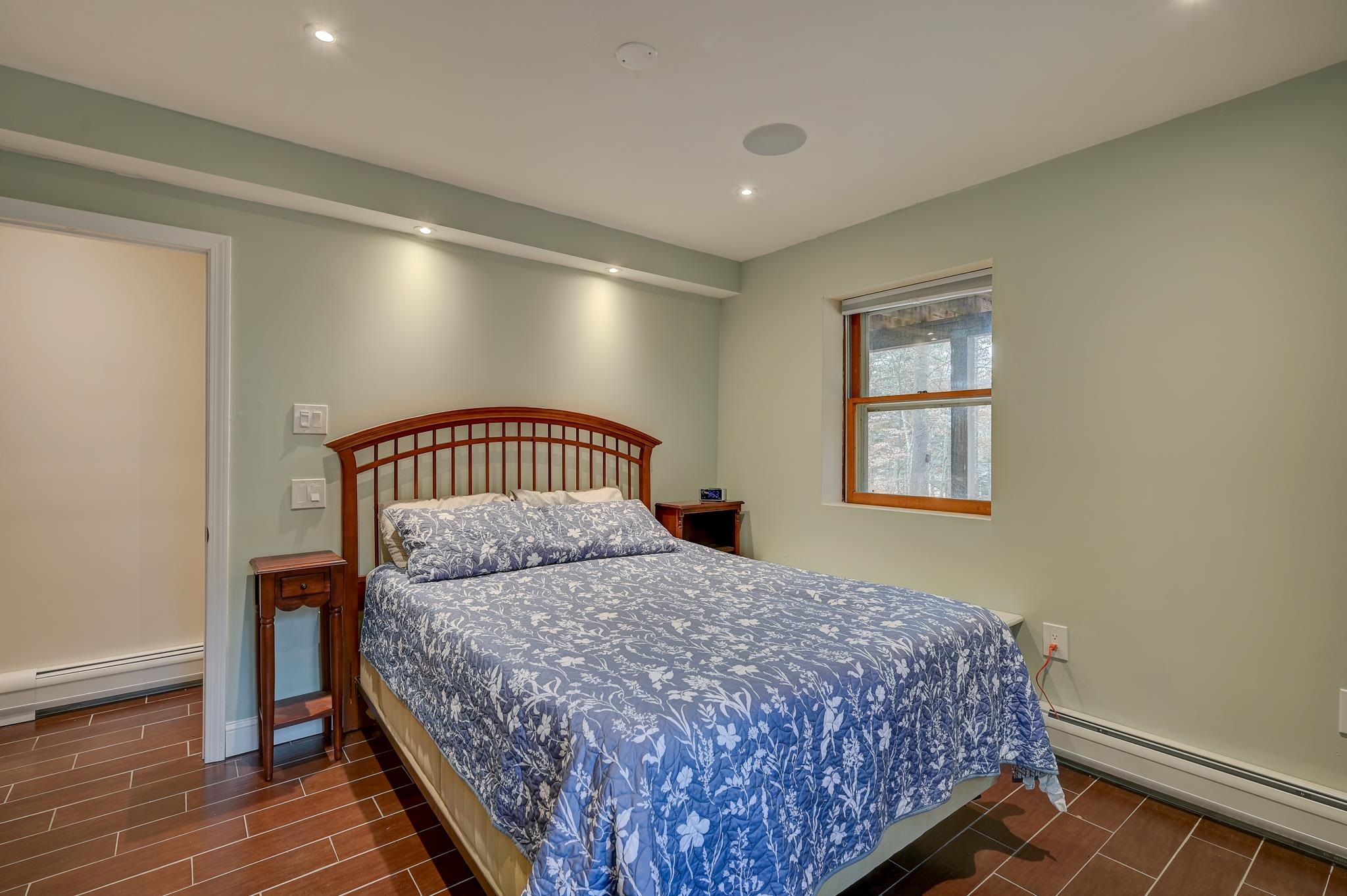 Bedroom with blue floral bedding, a curved wooden headboard, and reddish-brown tile flooring.
