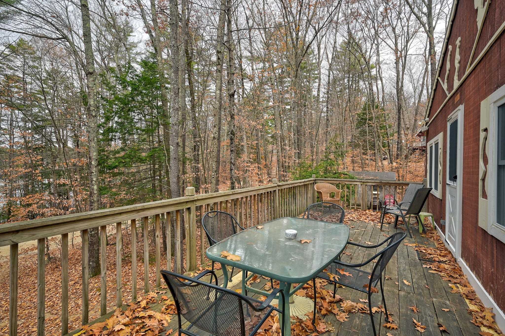 Wooden deck with patio furniture overlooking autumn woods.