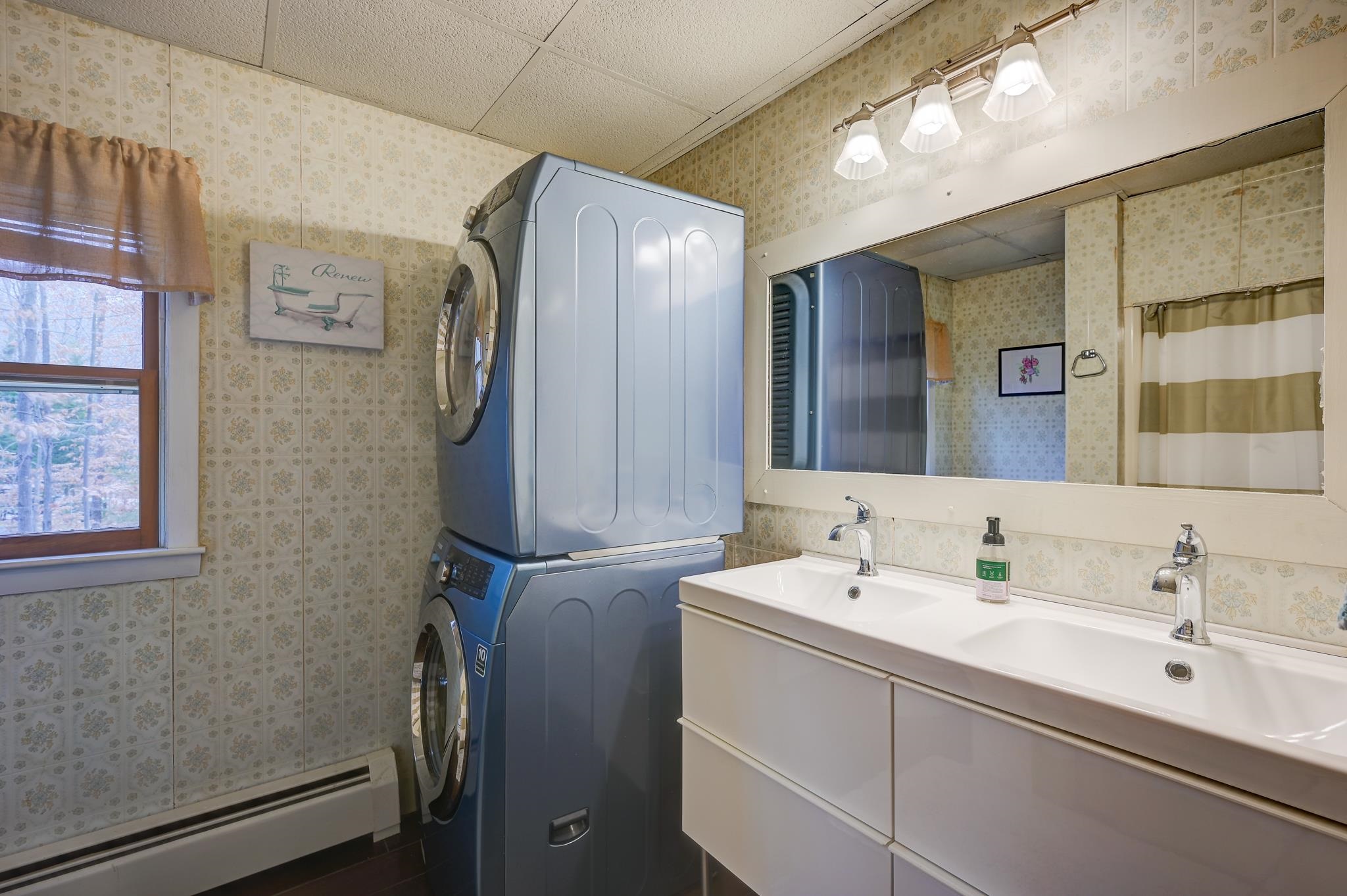 Bathroom with a double-sink vanity and stacked washer and dryer.