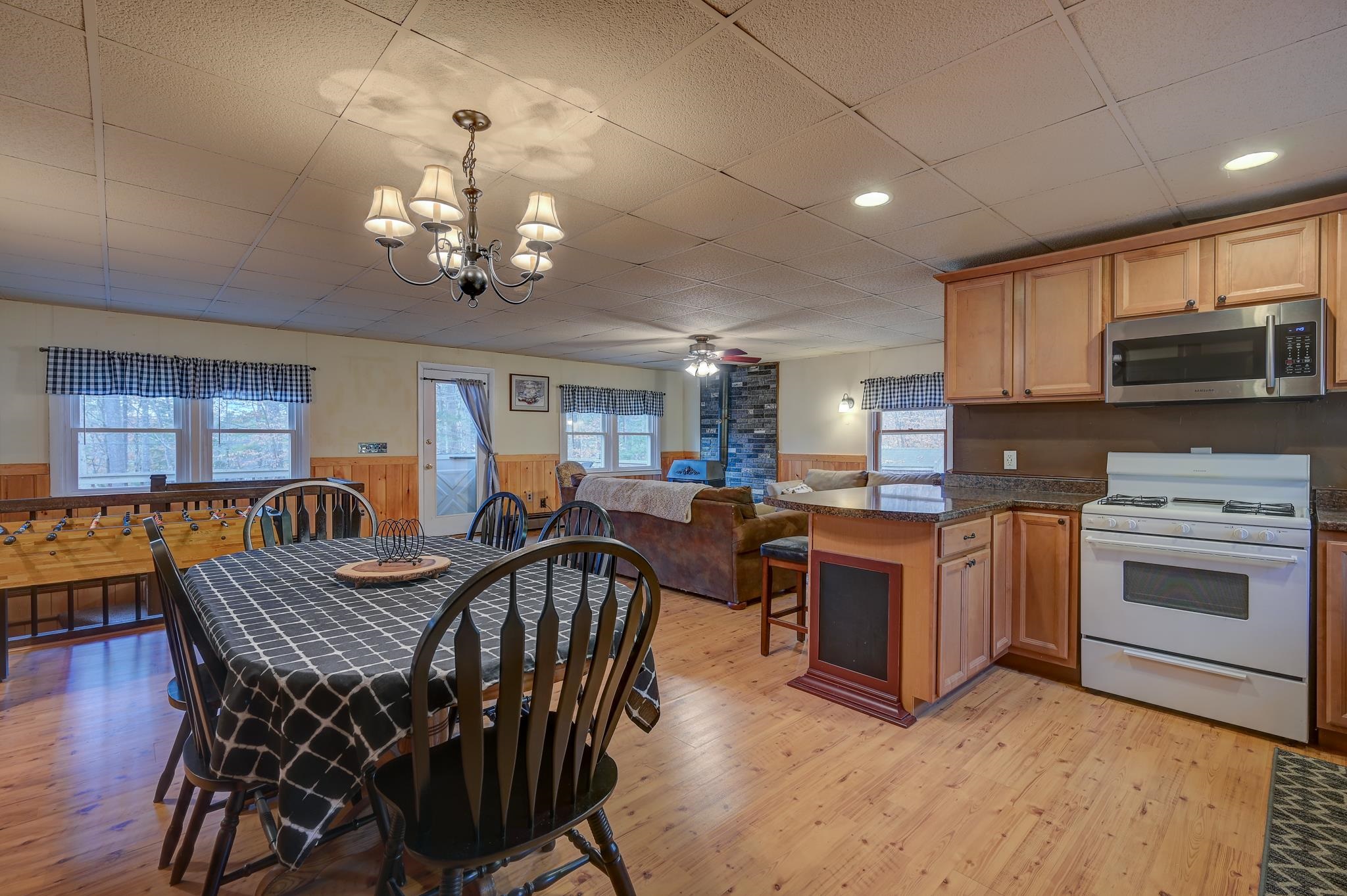 Open-plan kitchen and dining area with a wood island, foosball table, and adjoining living room.
