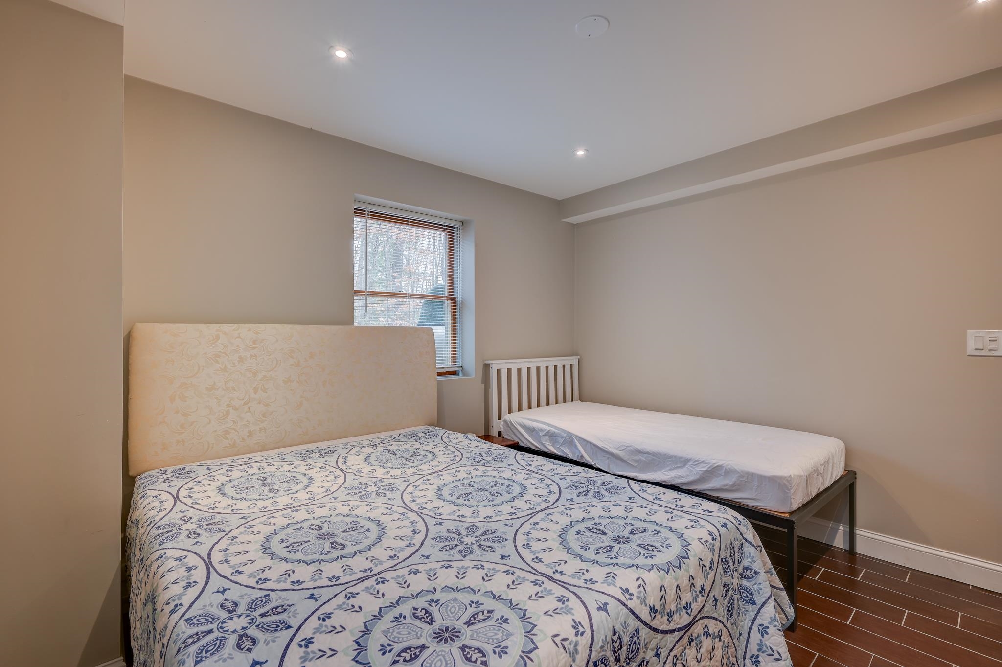 Bedroom with two beds, a blue-and-white patterned cover, and a window with blinds.