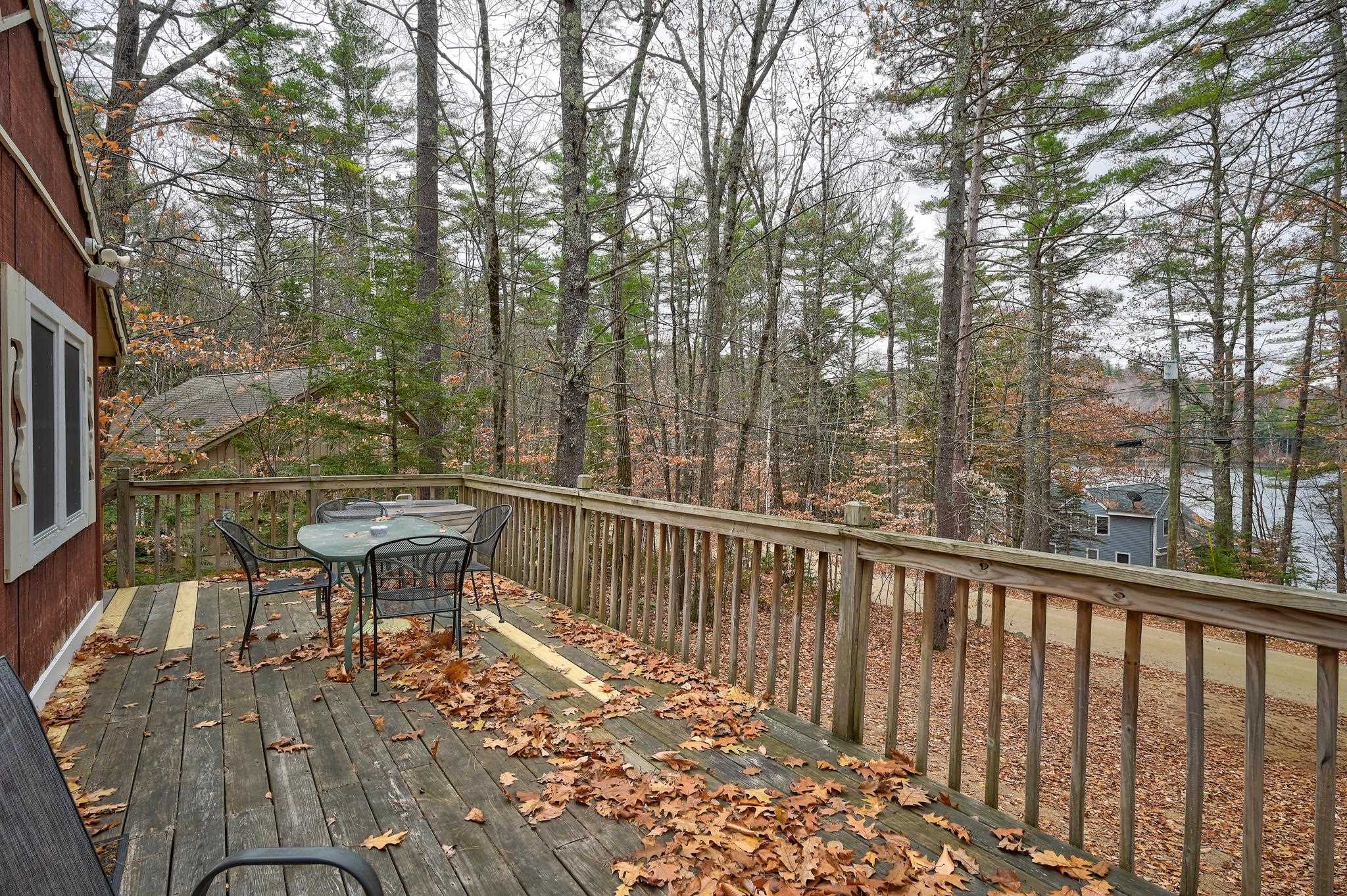 Wooden deck with outdoor dining set overlooking autumn woods and glimpses of water.