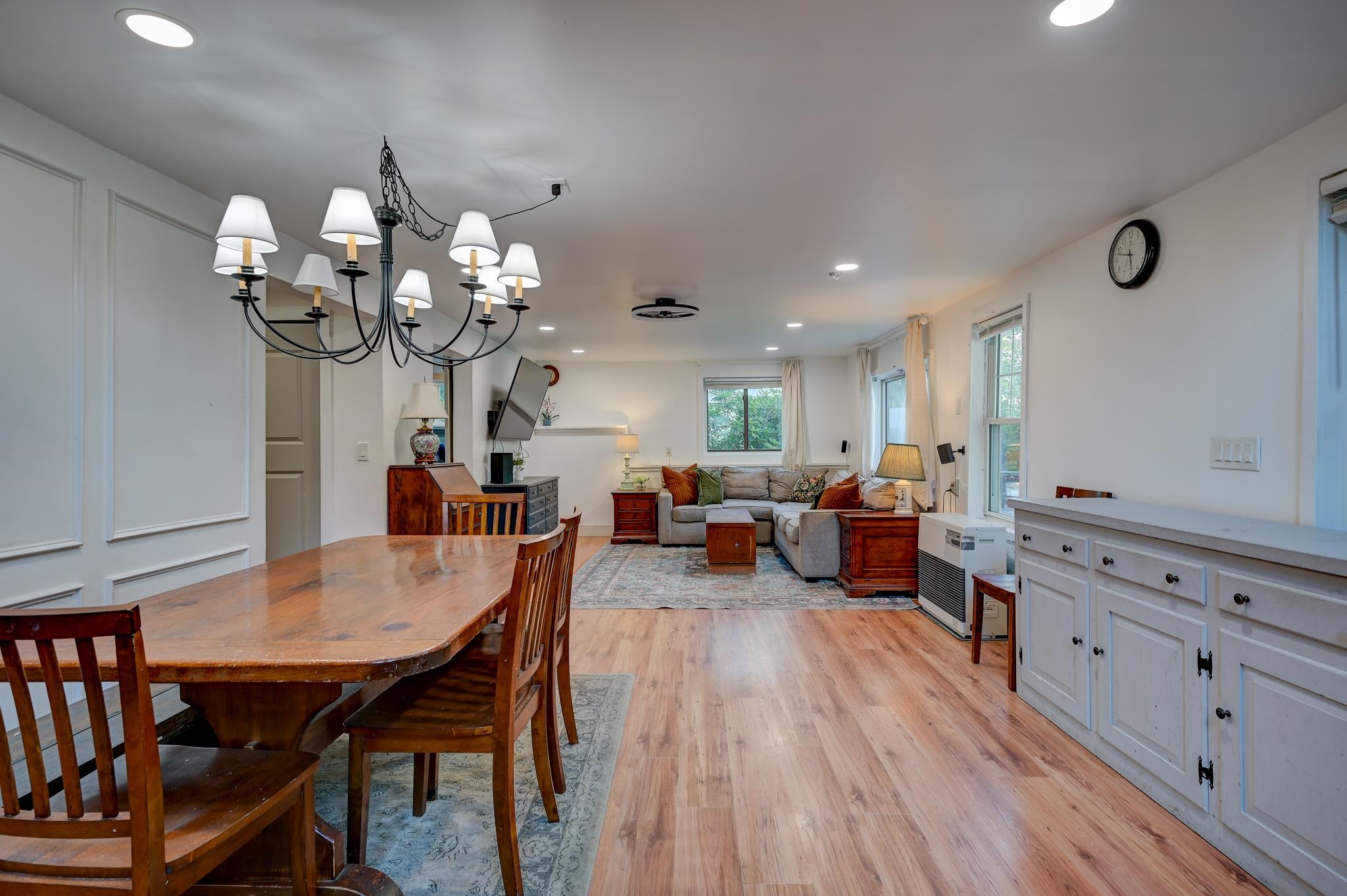 Open-plan living and dining room with a wooden dining set, gray sectional, and white built-in cabinets.