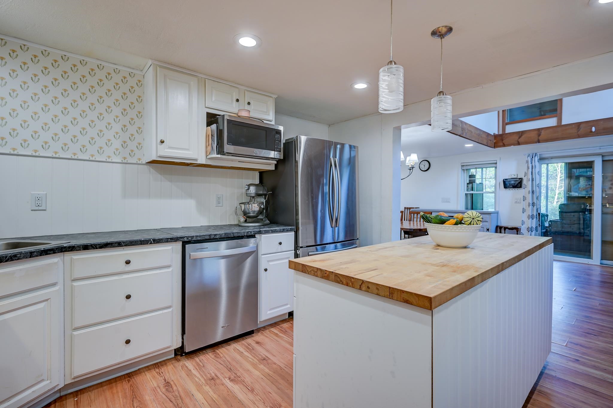 Kitchen with stainless steel appliances, floral wallpaper, and a large butcher-block island.