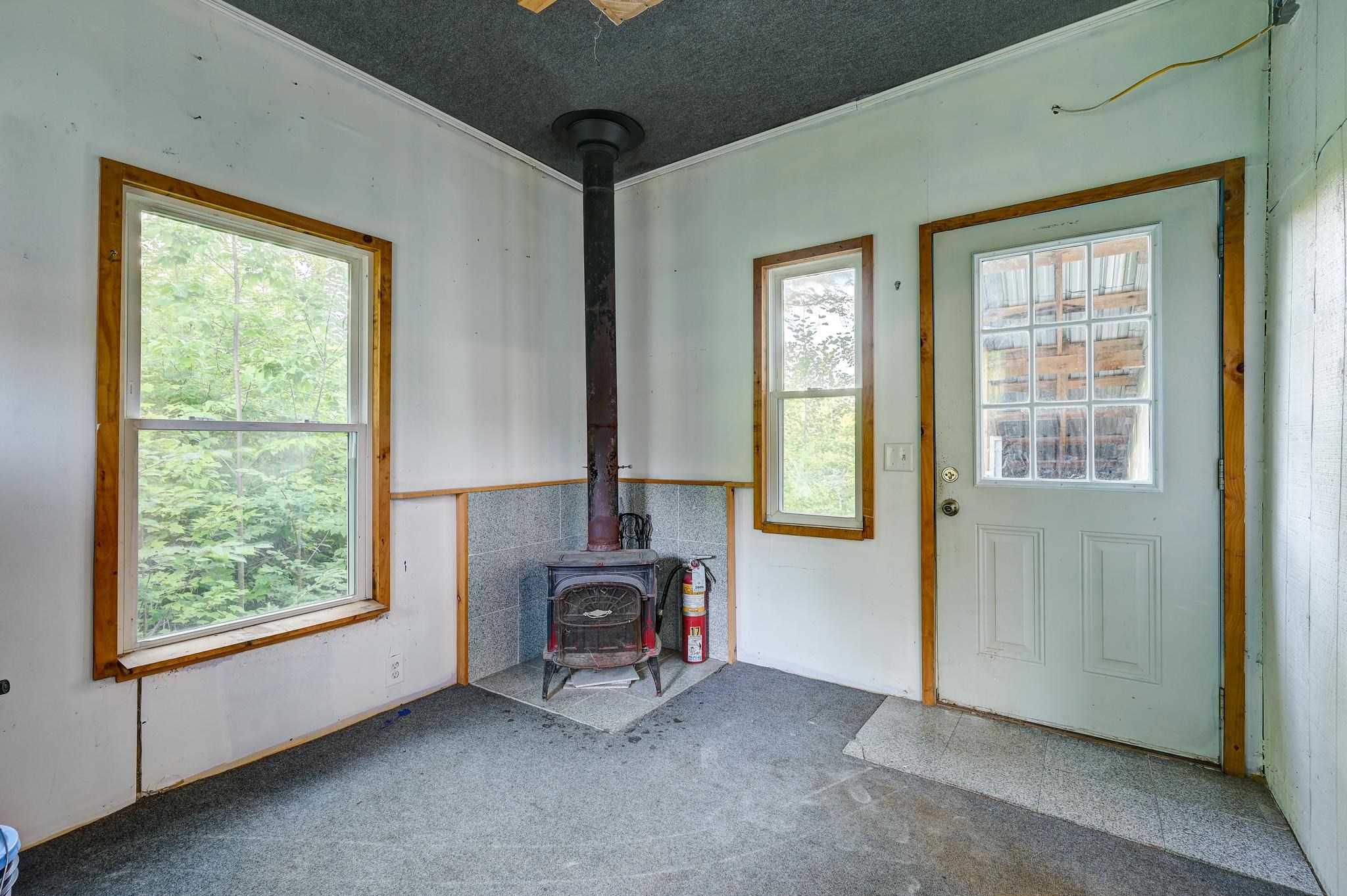 Entry room with a freestanding wood stove, two windows, and a pale green exterior door.