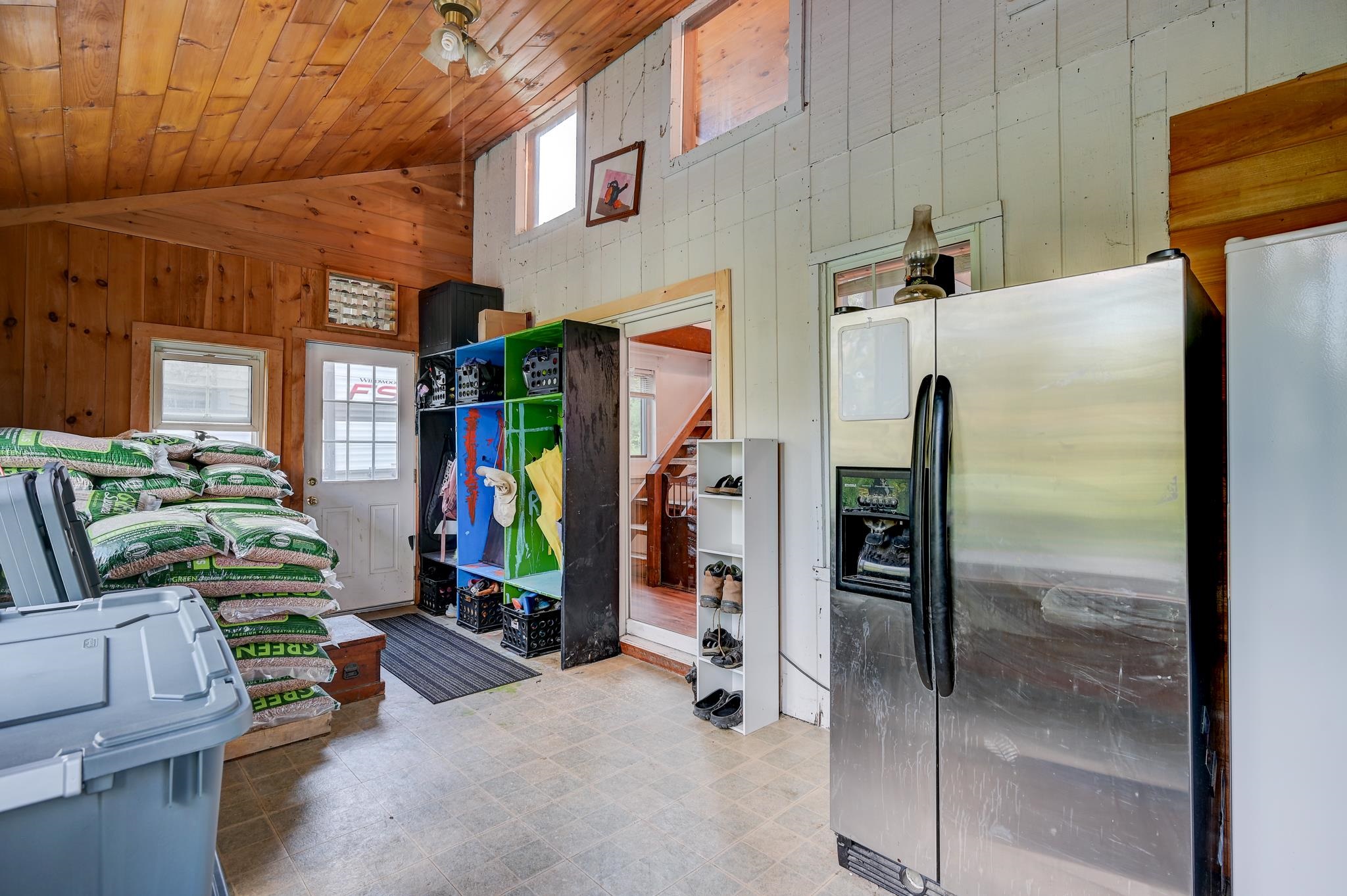 Utility room with a stainless steel refrigerator, colorful cubbies, and stacked bags of heating pellets.