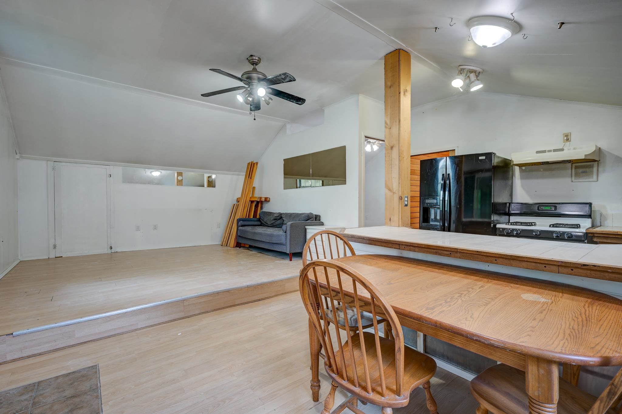 Kitchen and dining area with a long tiled counter, wooden table, and raised sitting area.
