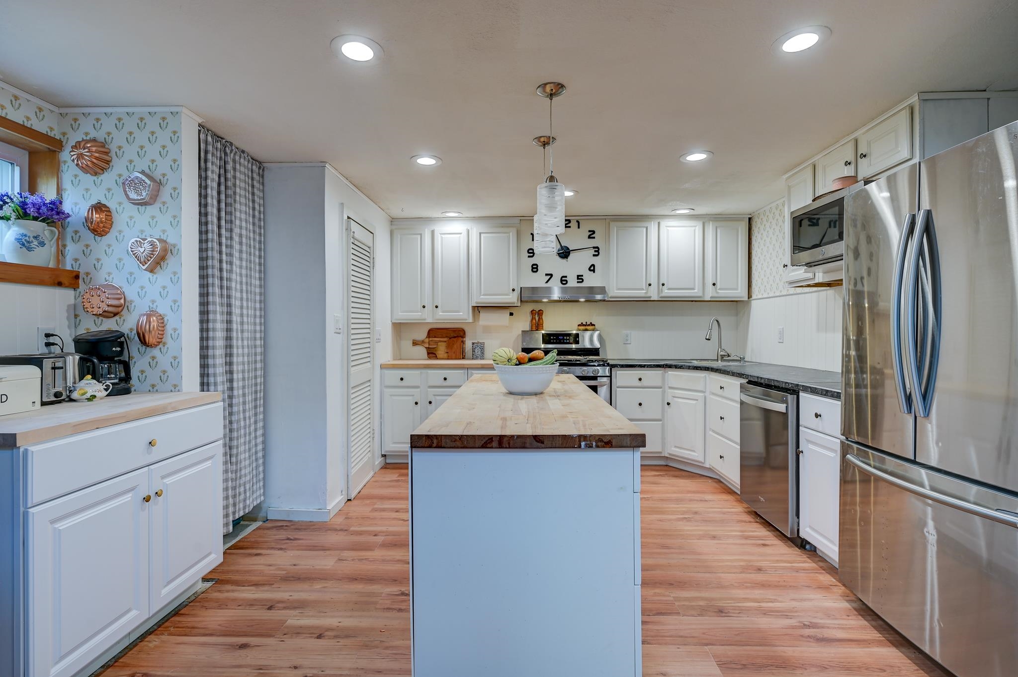 Kitchen with white cabinets, stainless steel appliances, and a butcher-block island.