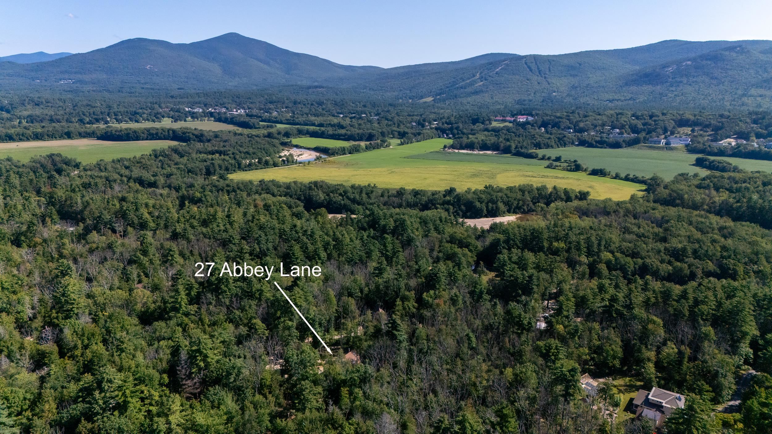 Aerial view of 27 Abbey Lane amid wooded land, with farmland and mountain ridges in the distance.