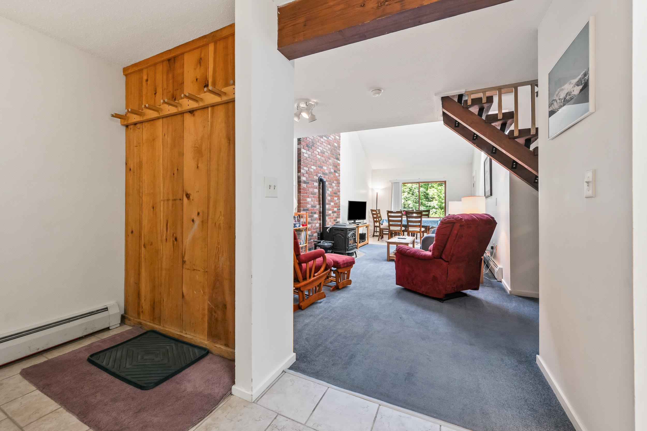Condo living room with a brick fireplace, red recliner, dining area, and staircase.