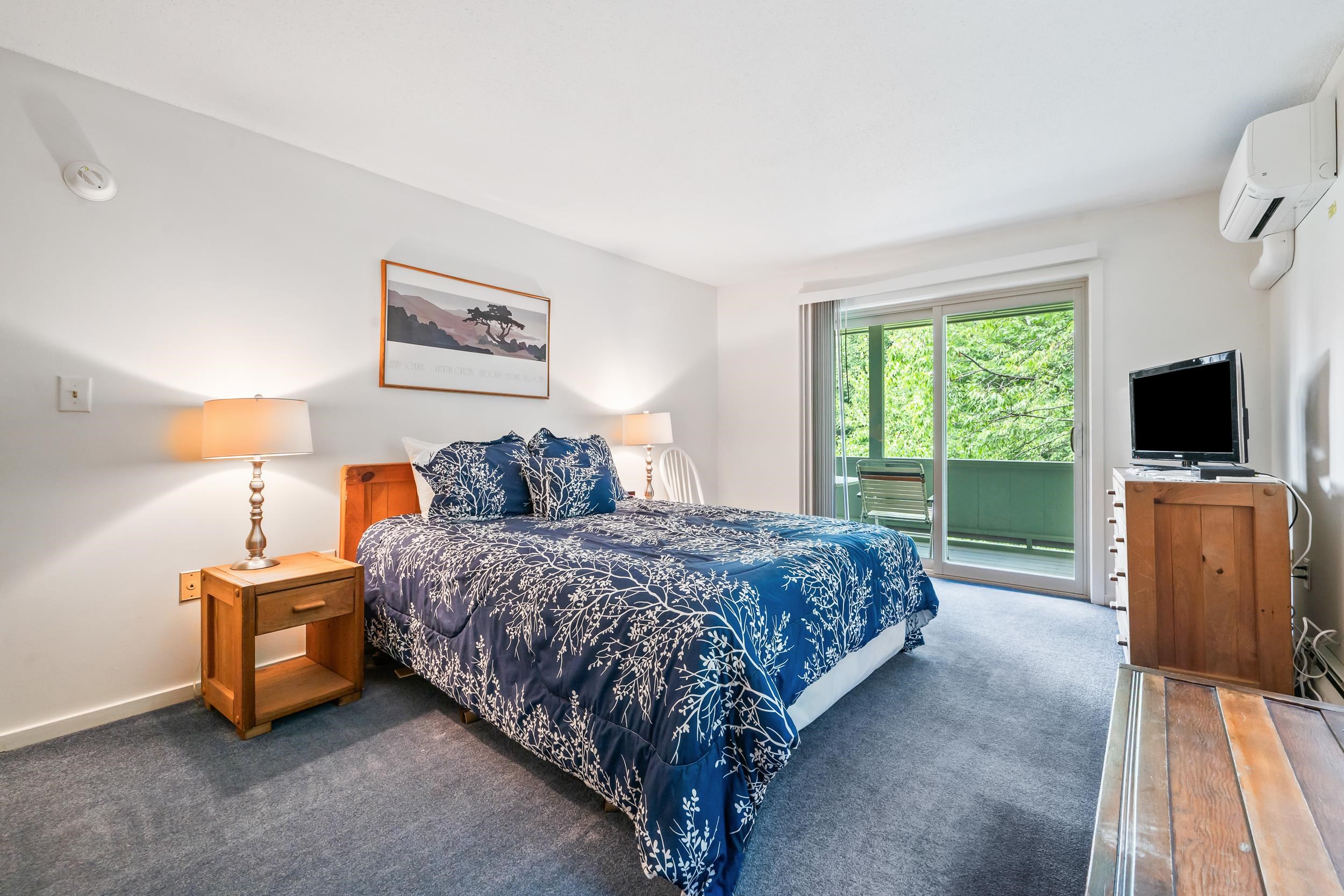 Bedroom with navy botanical bedding and sliding doors to a green balcony.