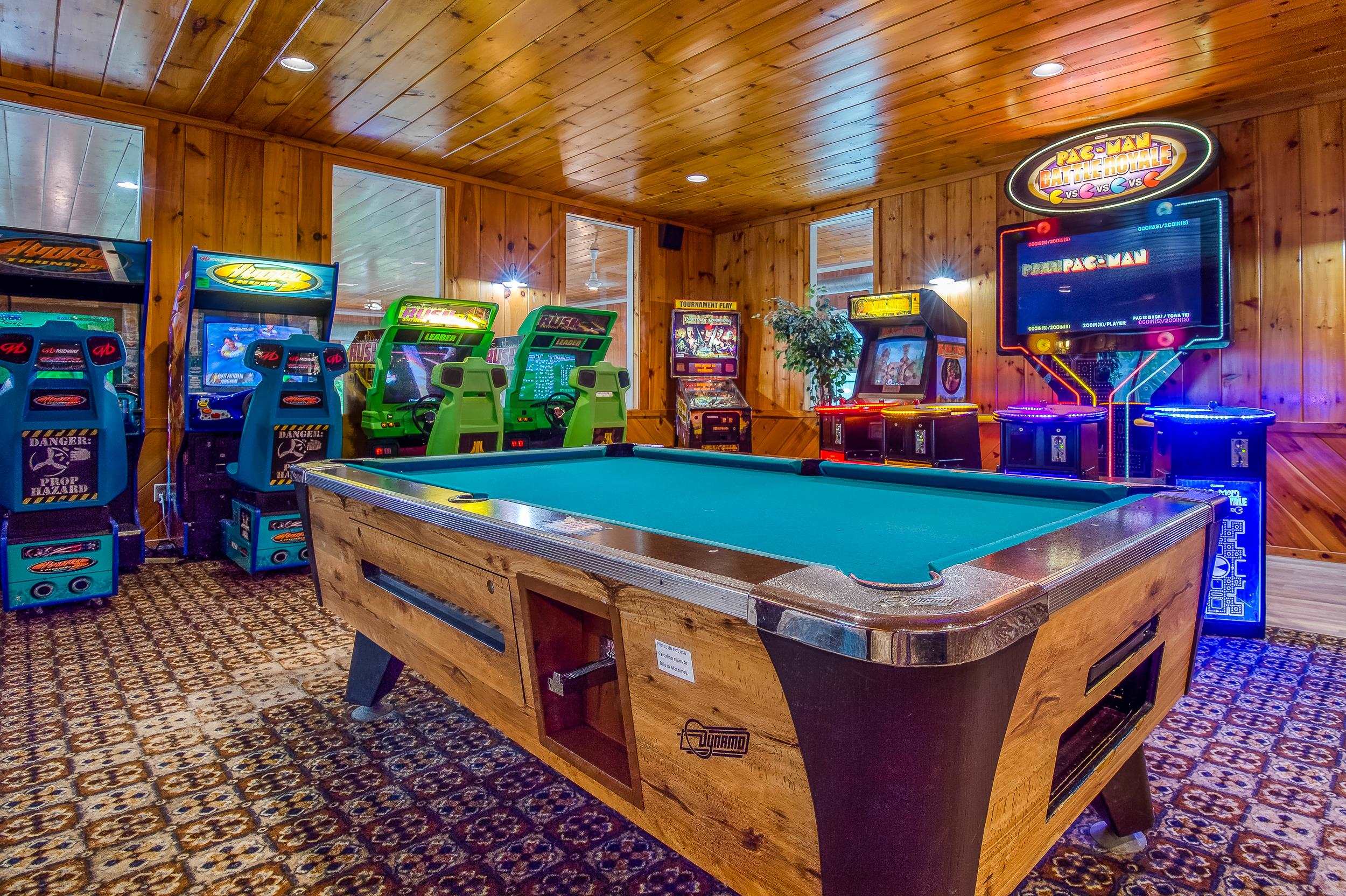 Game room with a full-size pool table and rows of colorful arcade games.