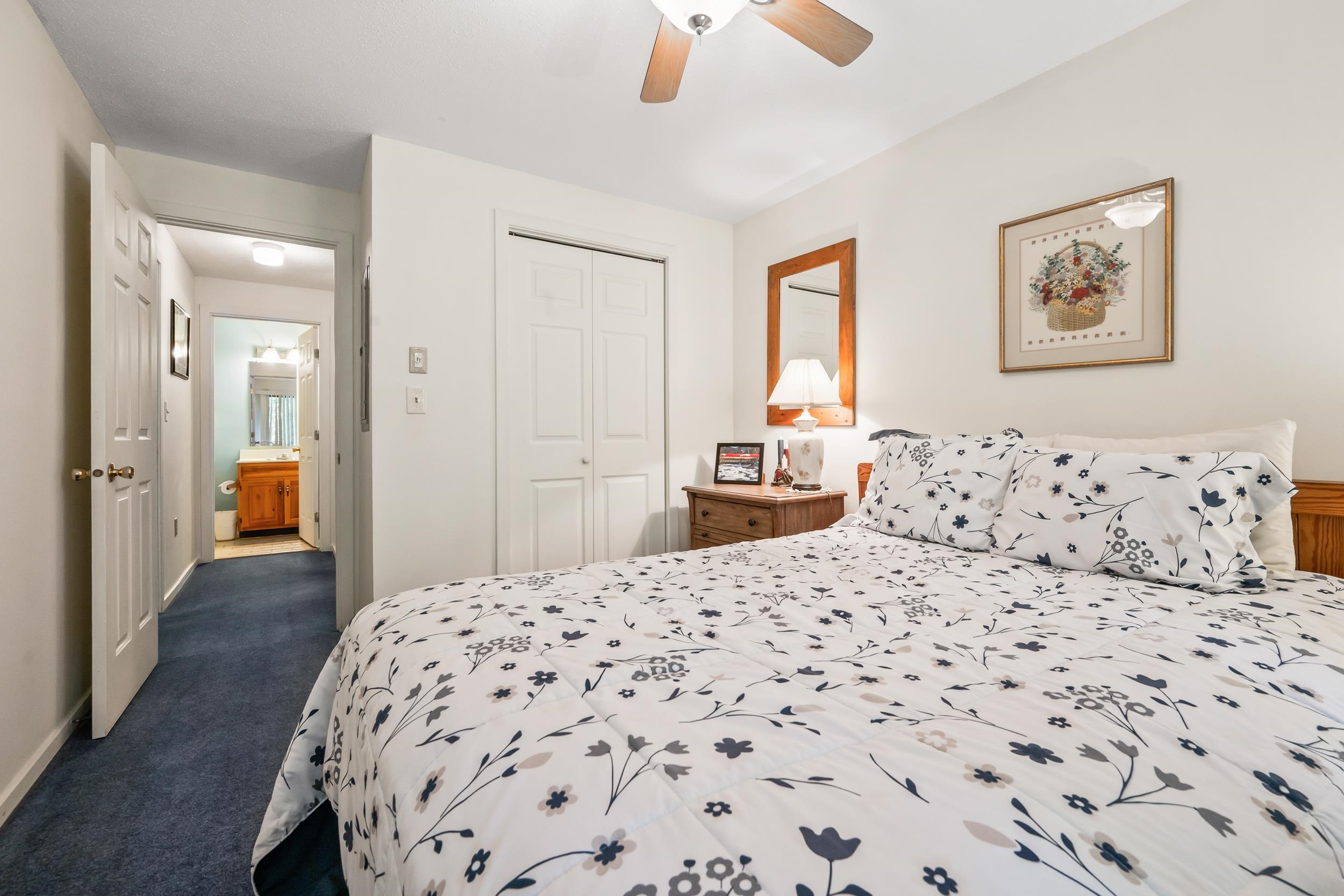 Bedroom with blue-and-gray floral bedding and an open doorway to the bathroom.