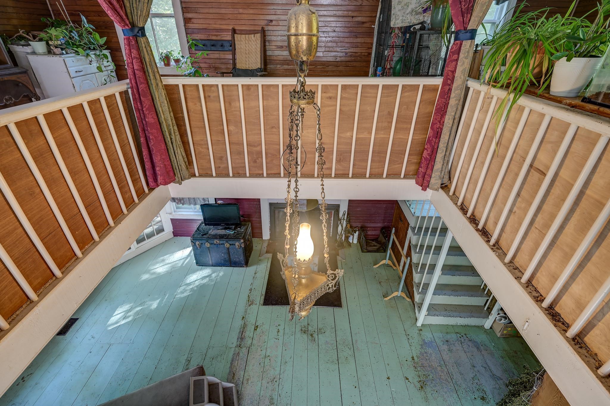 Two-story interior with a white-railed landing, turquoise floorboards, and an ornate hanging chandelier.