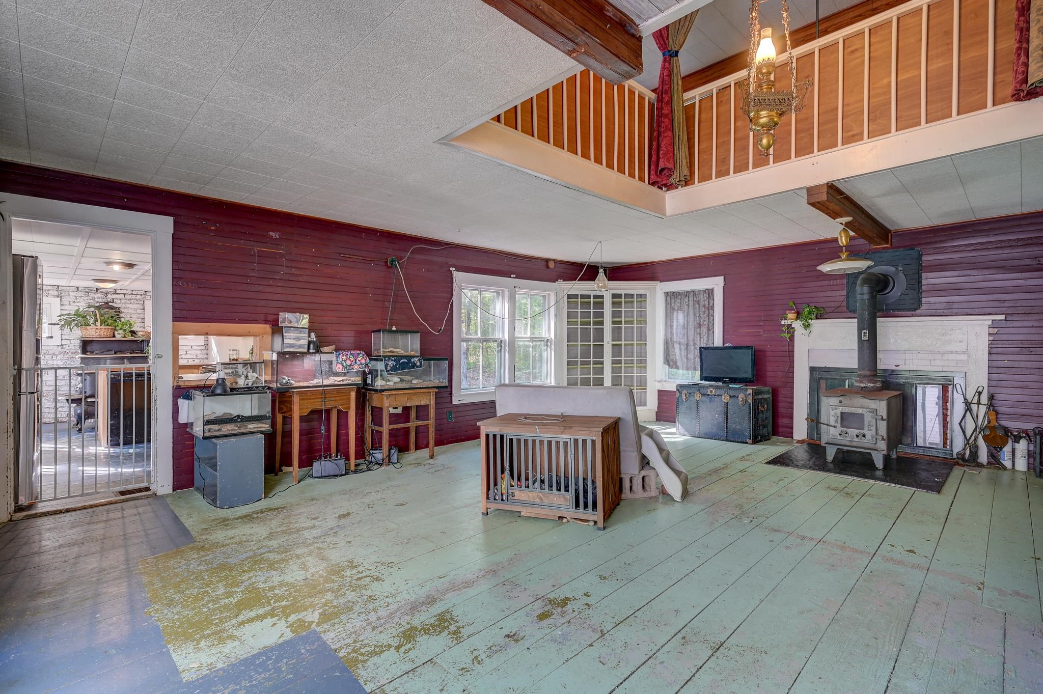 Living room with a loft, wood-burning stove, aquariums, and distressed plank floors.