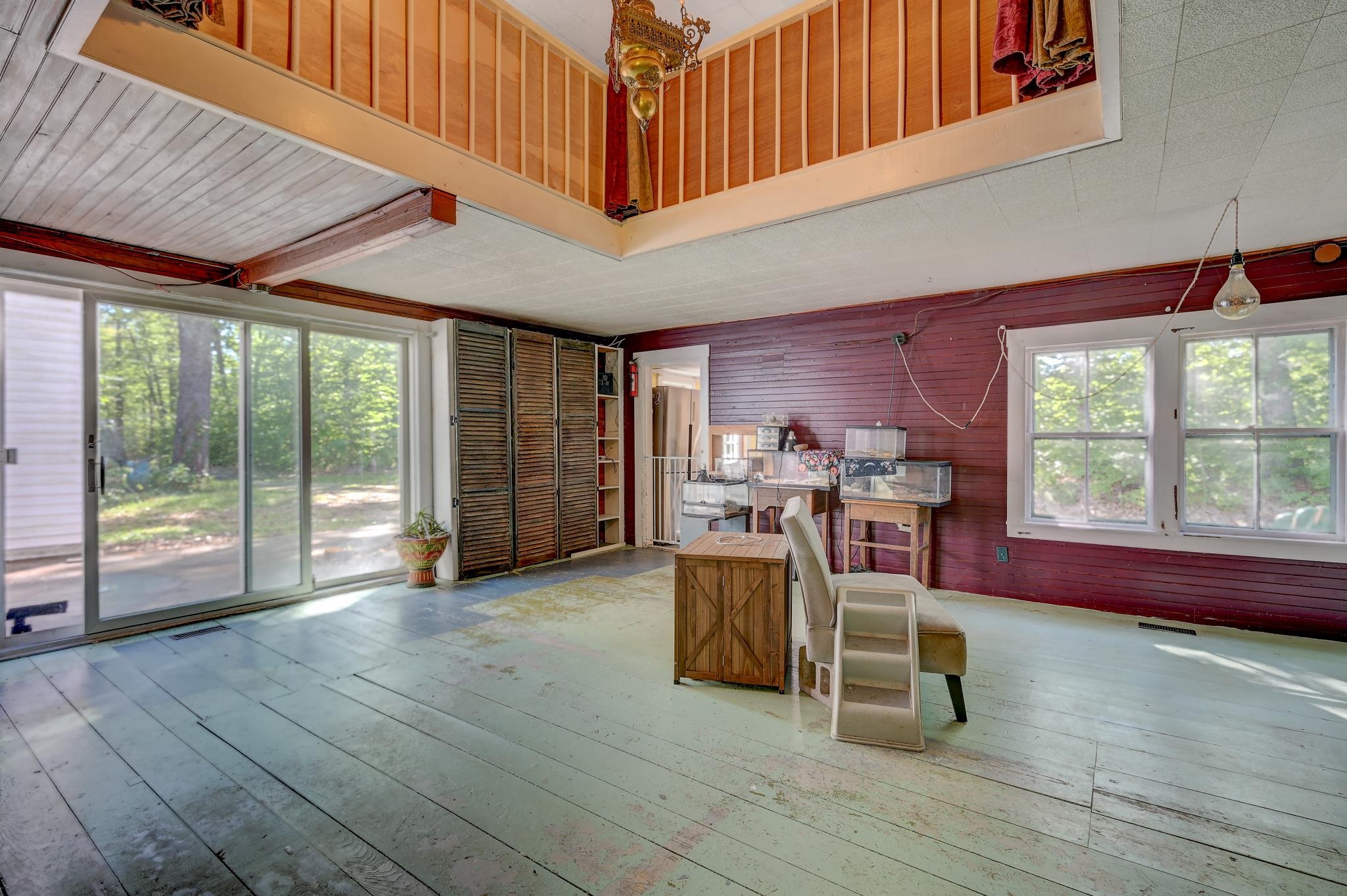 Spacious room with an open loft, burgundy paneled wall, aquariums, and sliding glass doors to the trees.