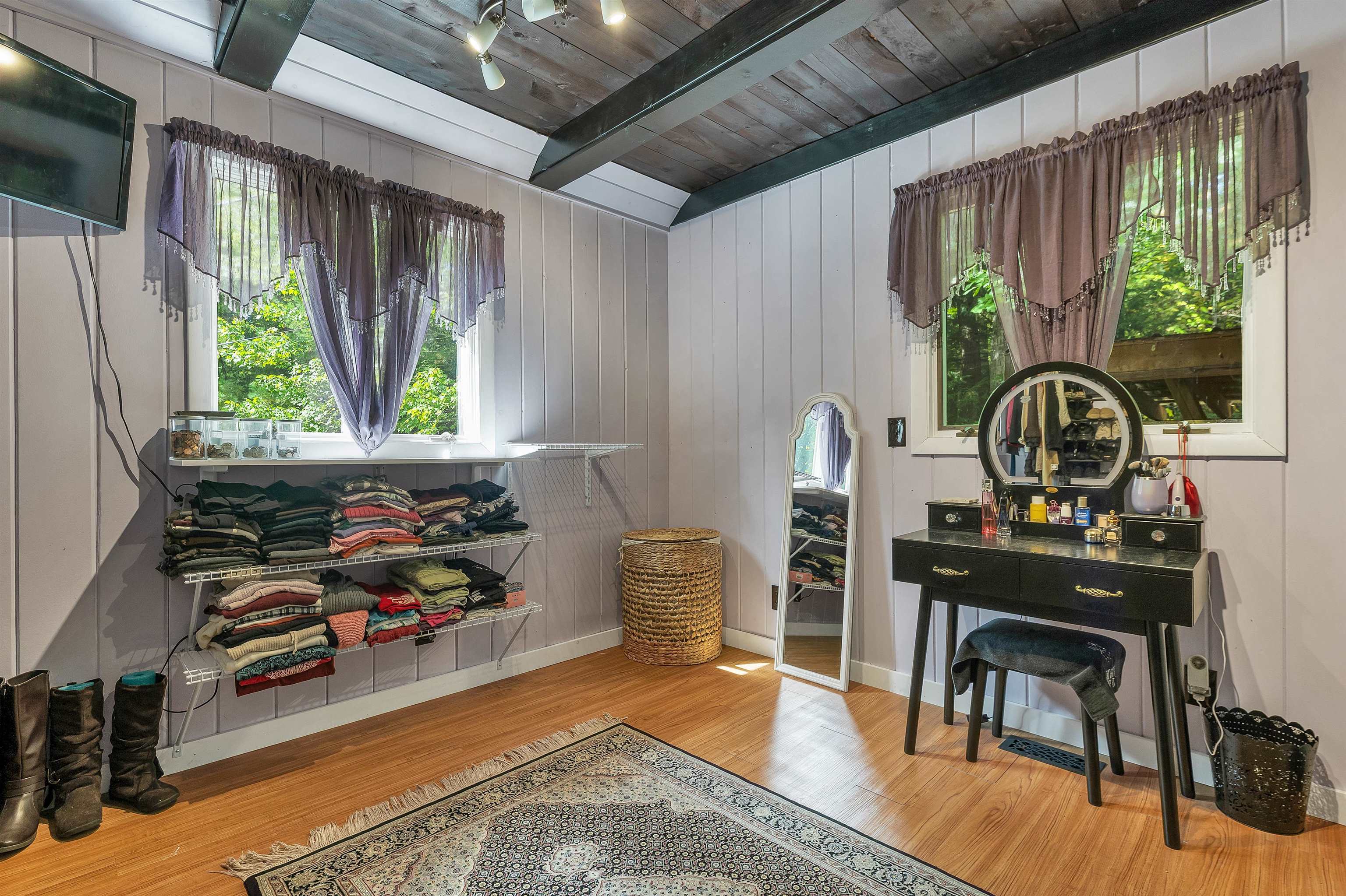 Dressing room with open clothing shelves, a black vanity, and a full-length mirror.