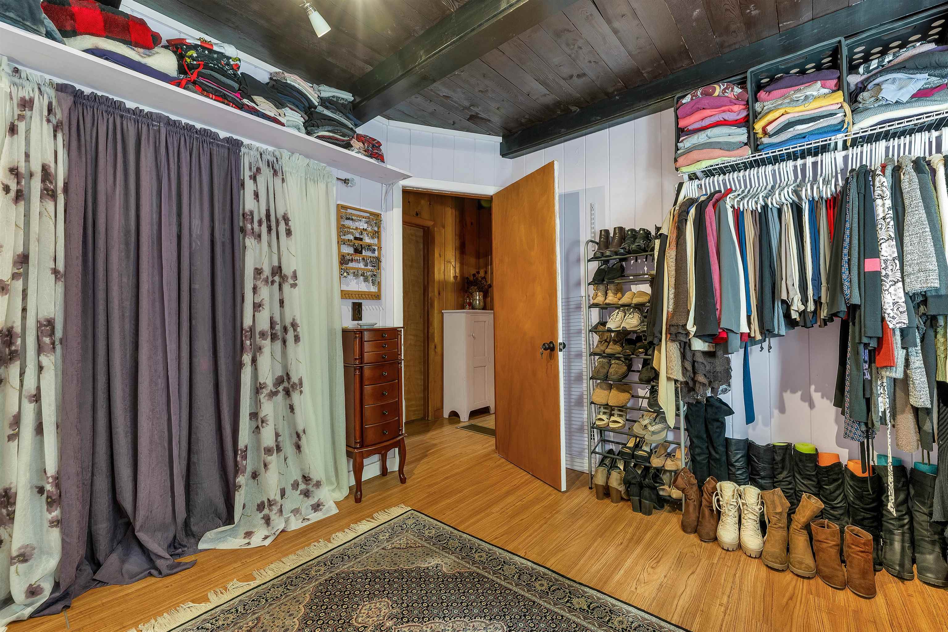 Walk-in closet with clothing racks, shelves of folded garments, and rows of shoes and boots.