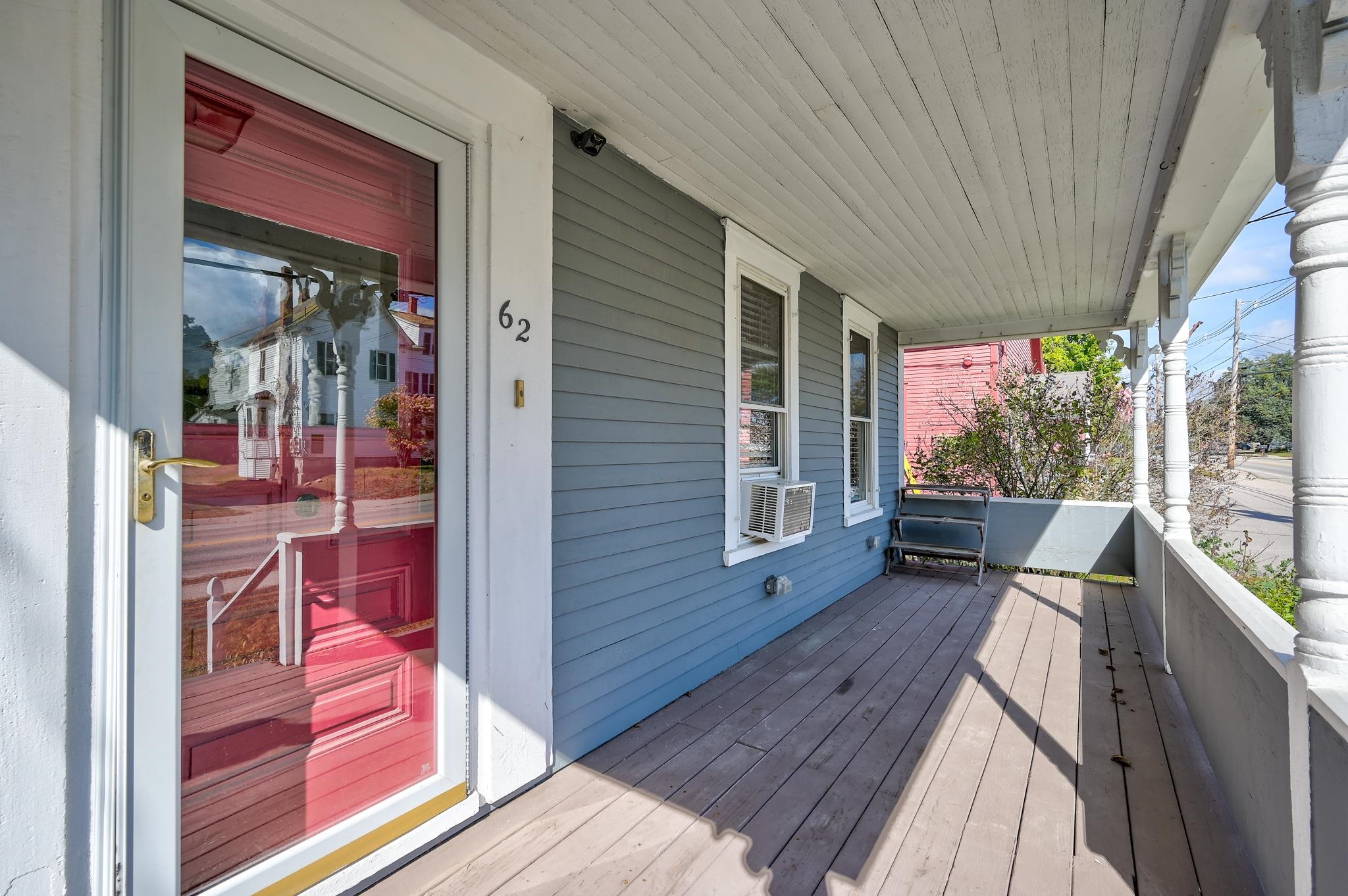 Covered front porch with a red entry door, blue-gray siding, and white columns.