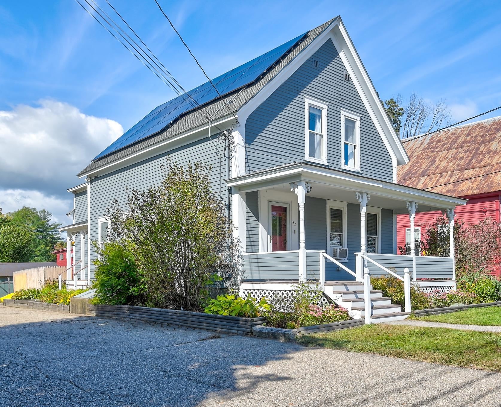 Blue two-story house with a covered porch and rooftop solar panels.