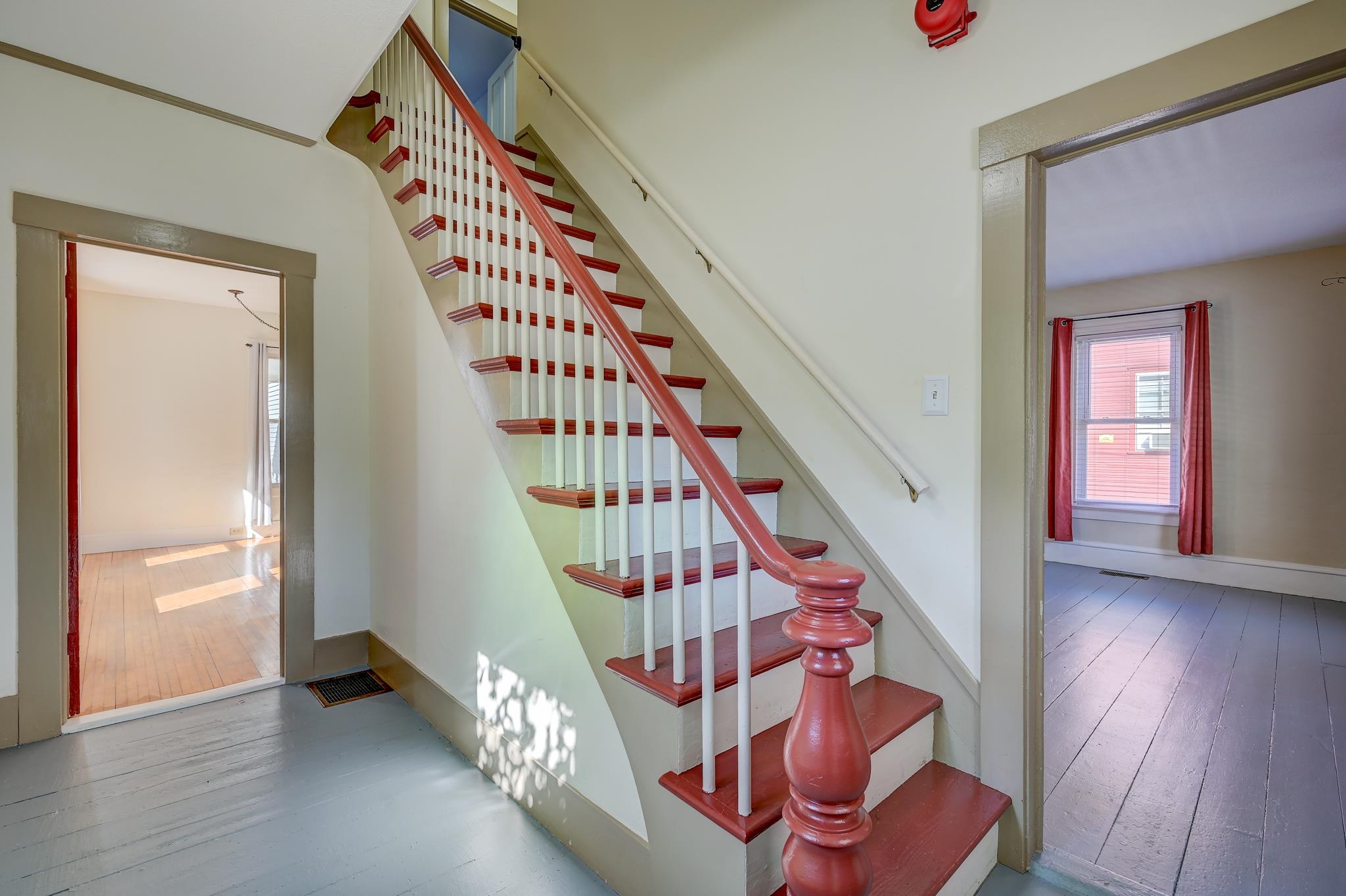 Staircase with red-painted treads and handrail, white balusters, and doorways to adjoining rooms.