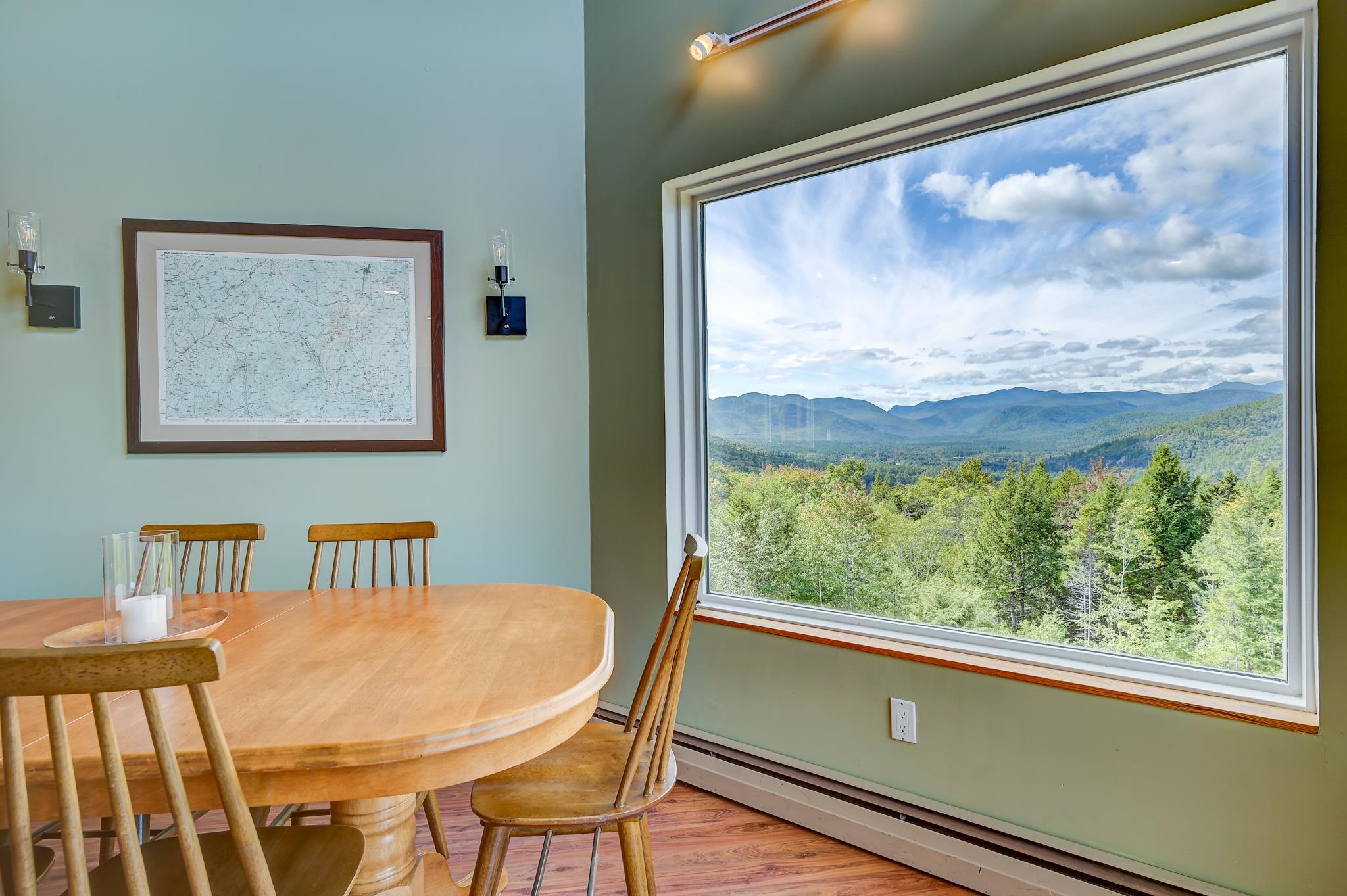 Dining area with a large picture window overlooking forested mountains.
