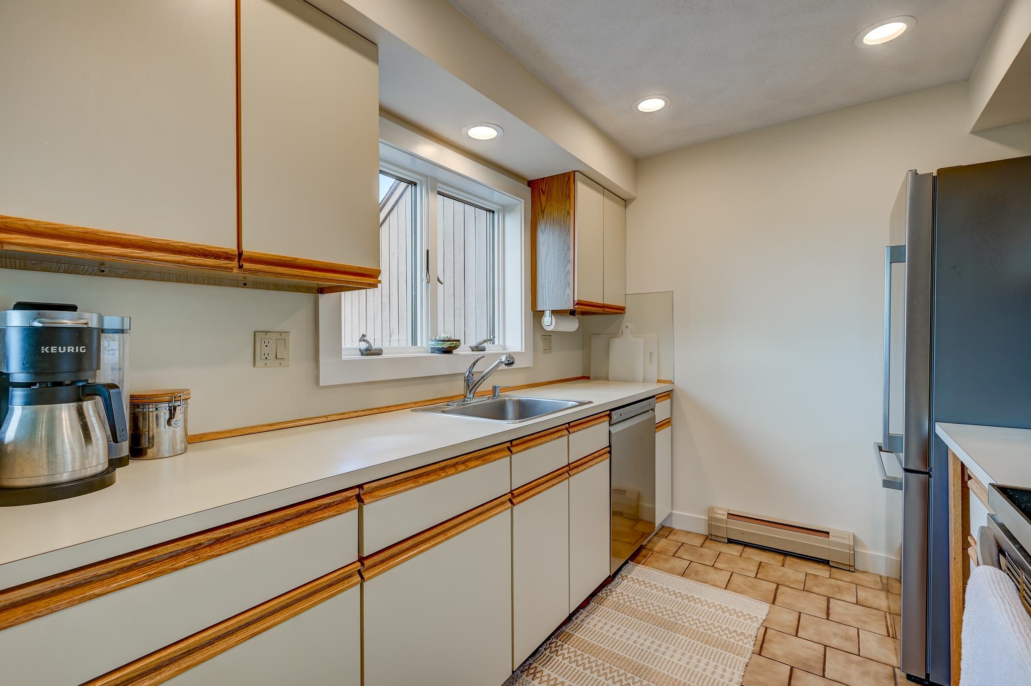 Kitchen with white cabinets and wood trim, a window over the sink, and stainless-steel appliances.
