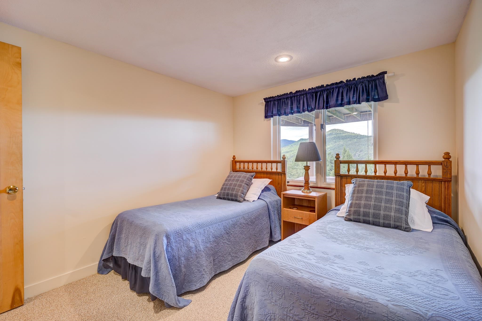 Twin bedroom with wooden headboards and a mountain view through the window.
