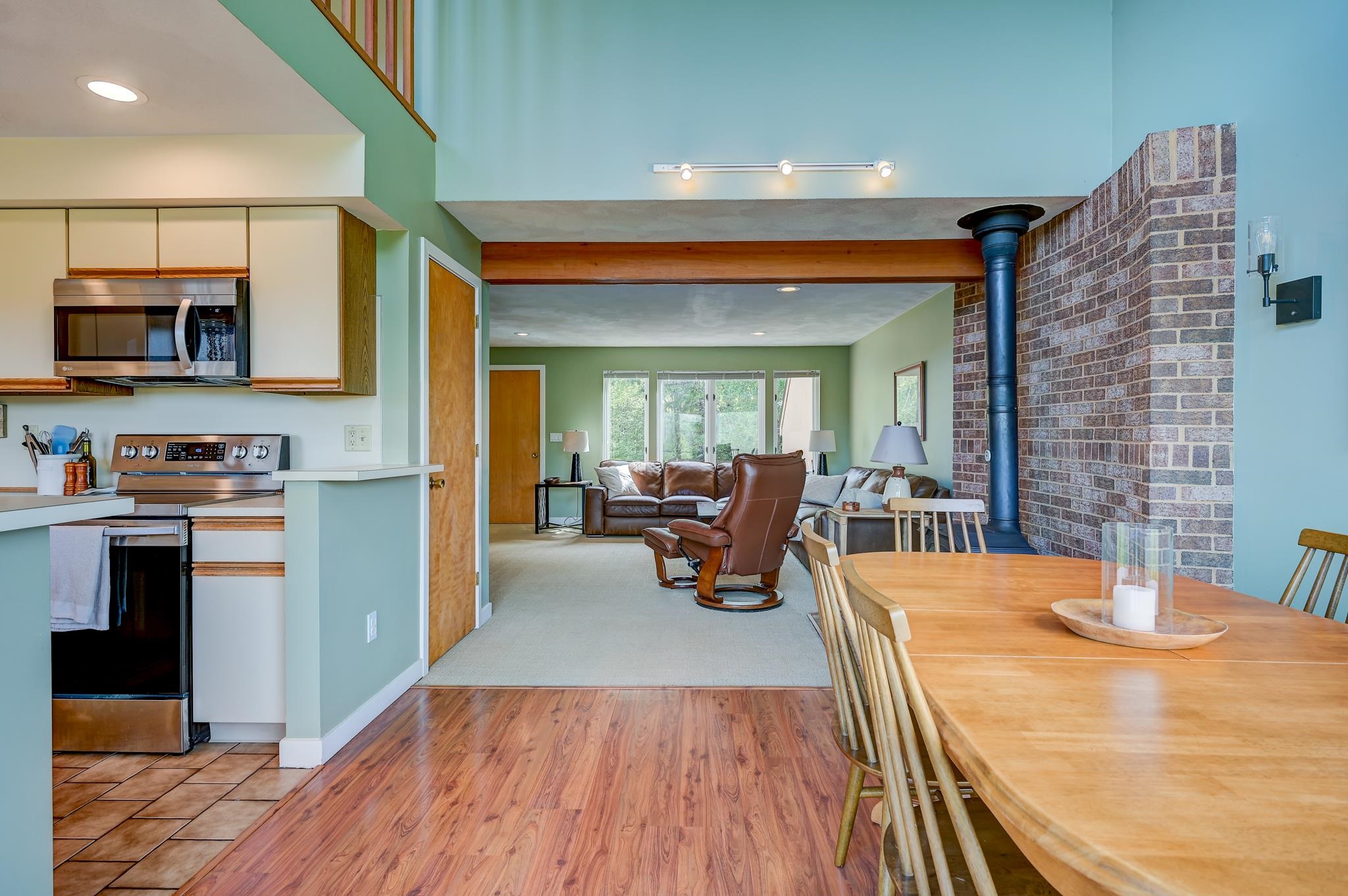 Open-plan kitchen, dining area, and living room with a brick fireplace and leather seating.