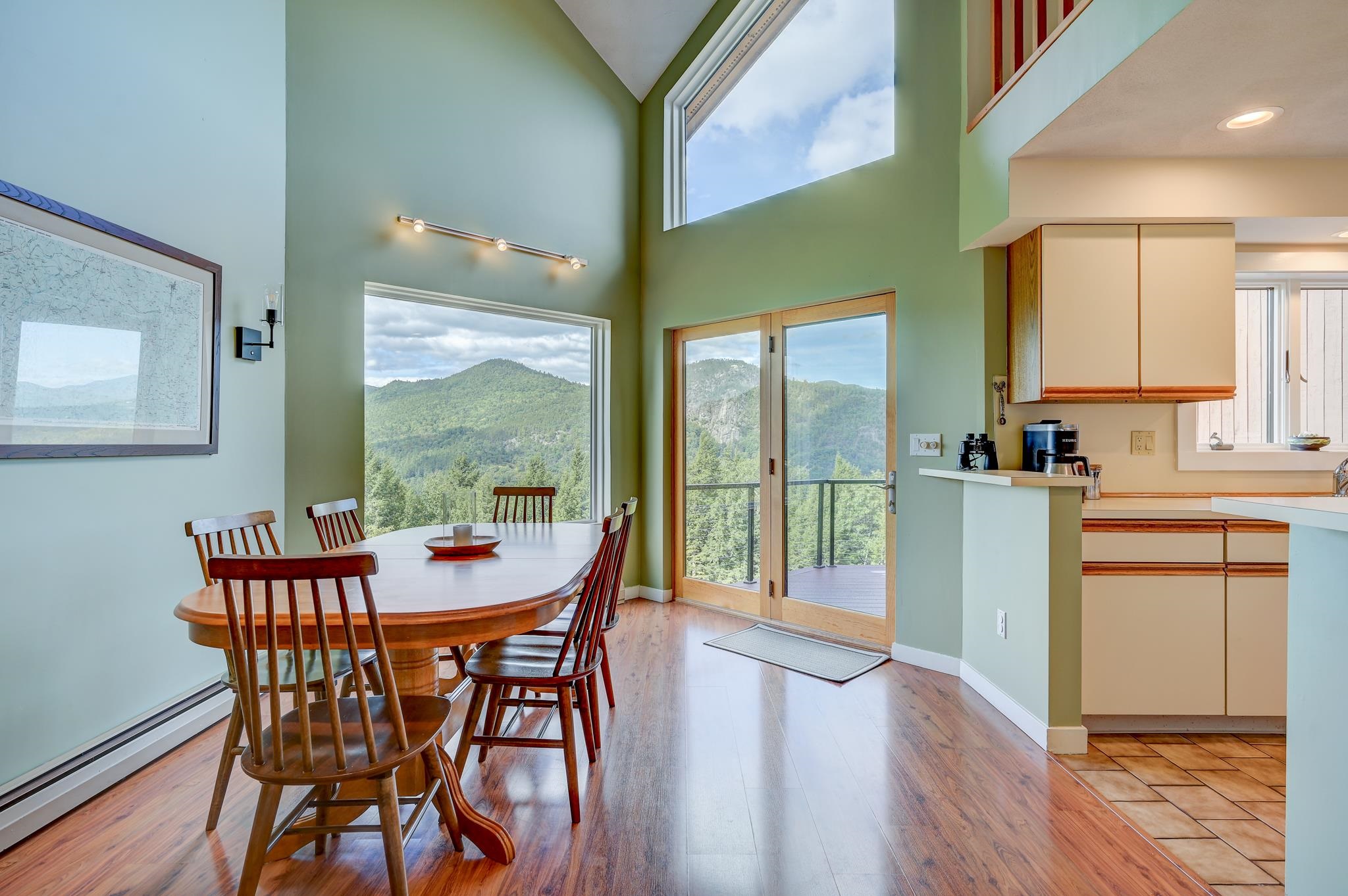 Dining area with vaulted ceilings and mountain views through large windows and glass doors.
