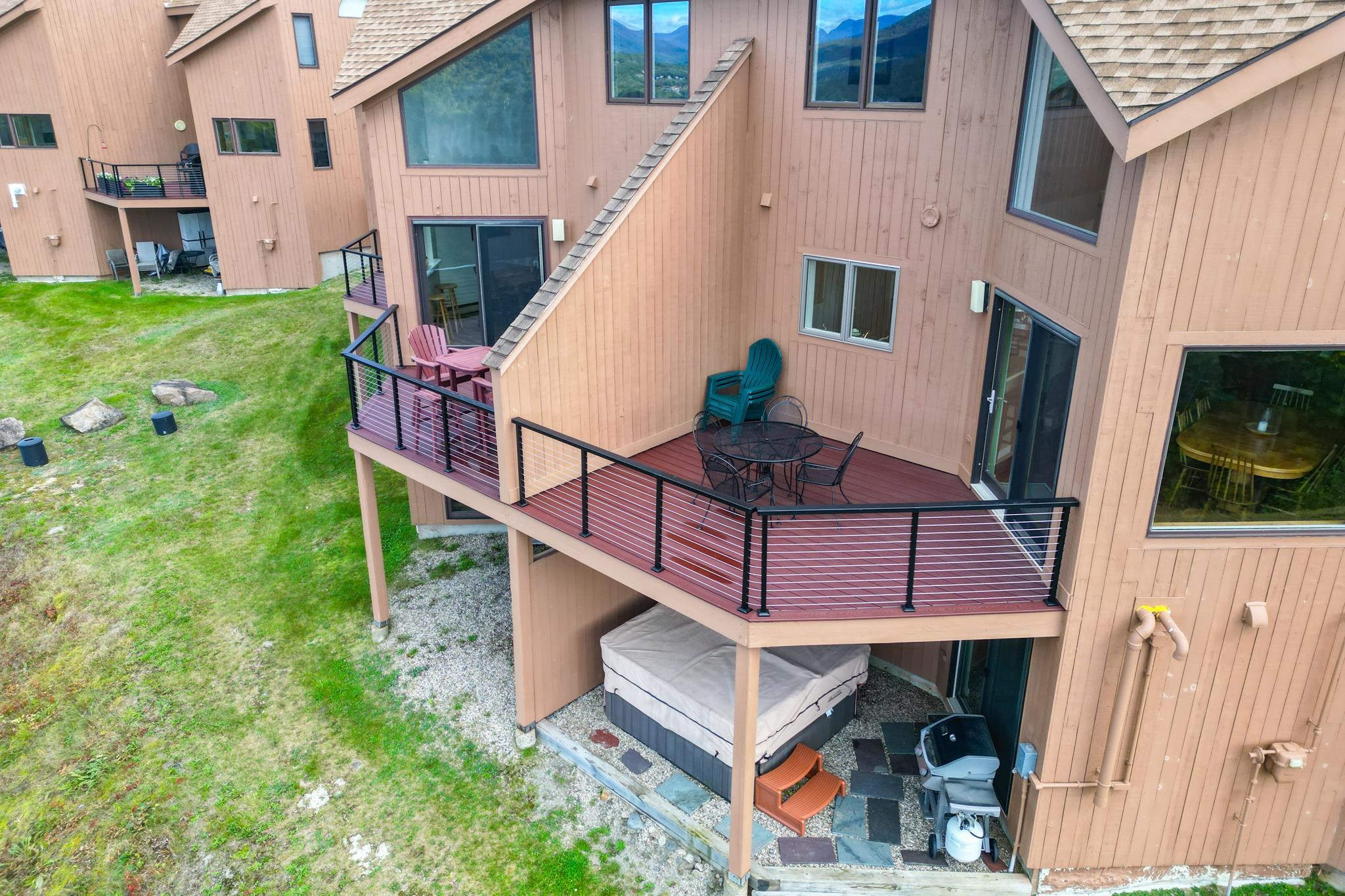 Condominium exterior with raised decks, patio furniture, and a covered hot tub beneath the main deck.