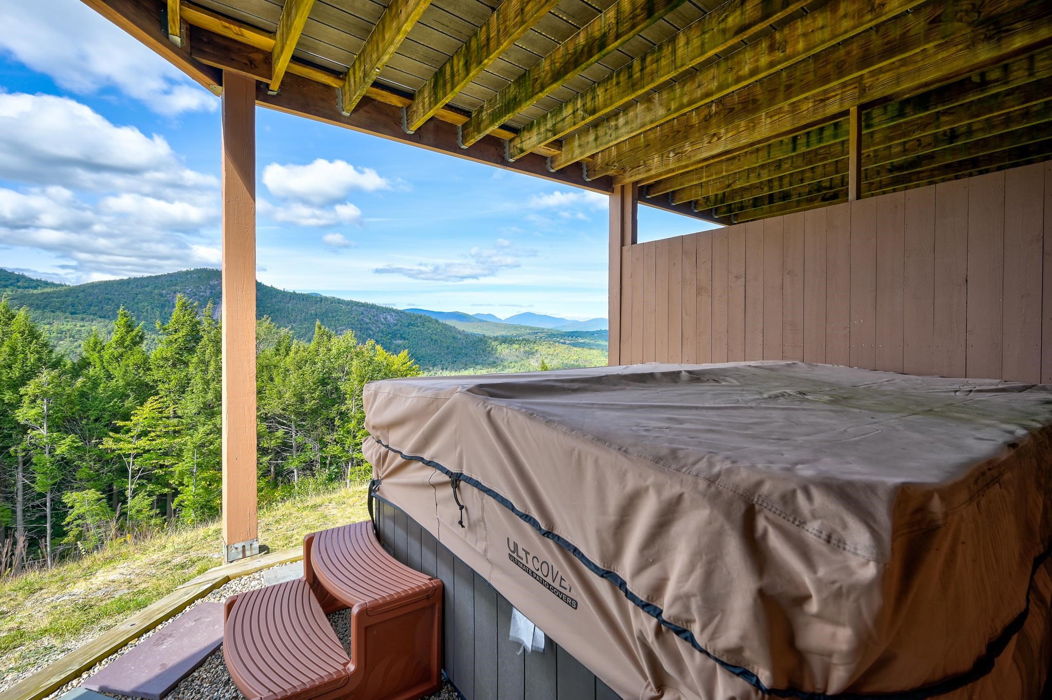 Covered hot tub on a mountain-view deck beneath a timber roof.