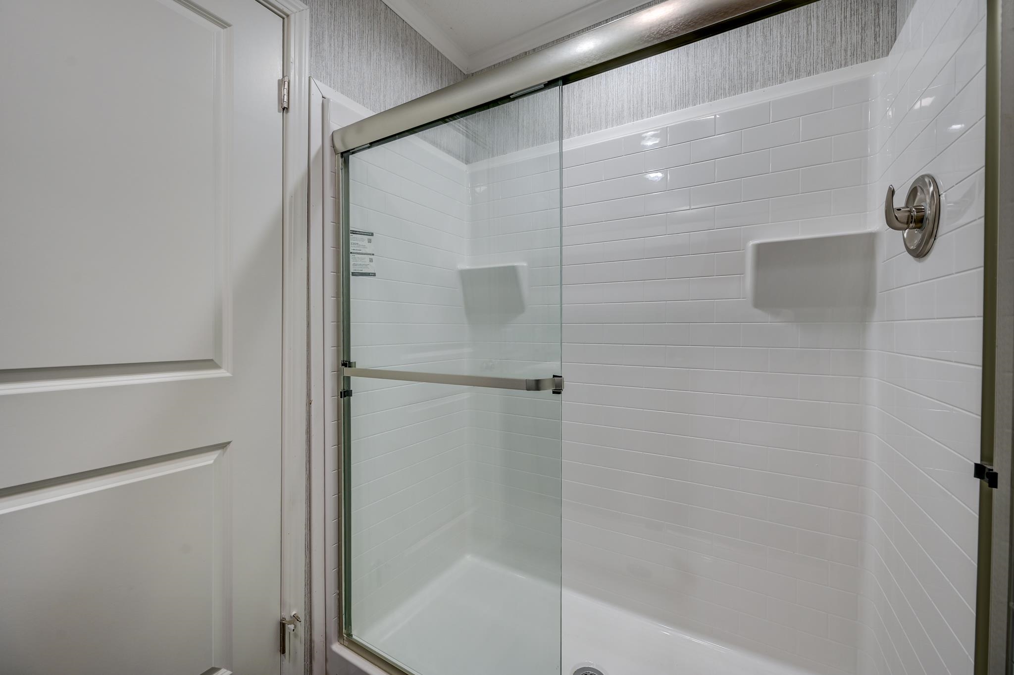 Bathroom shower with a clear glass enclosure, white subway tile, and chrome controls.