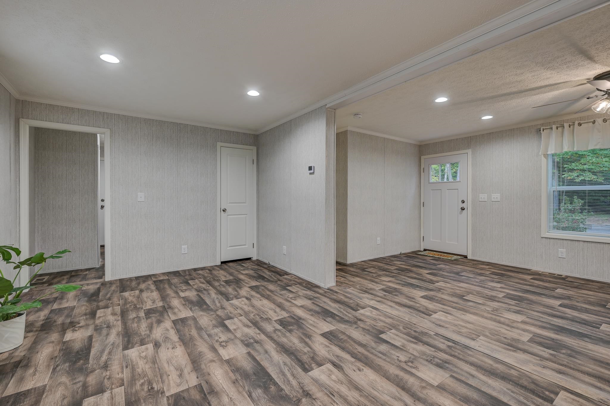 Mostly empty room with wood-look plank flooring, a front door, and a window.