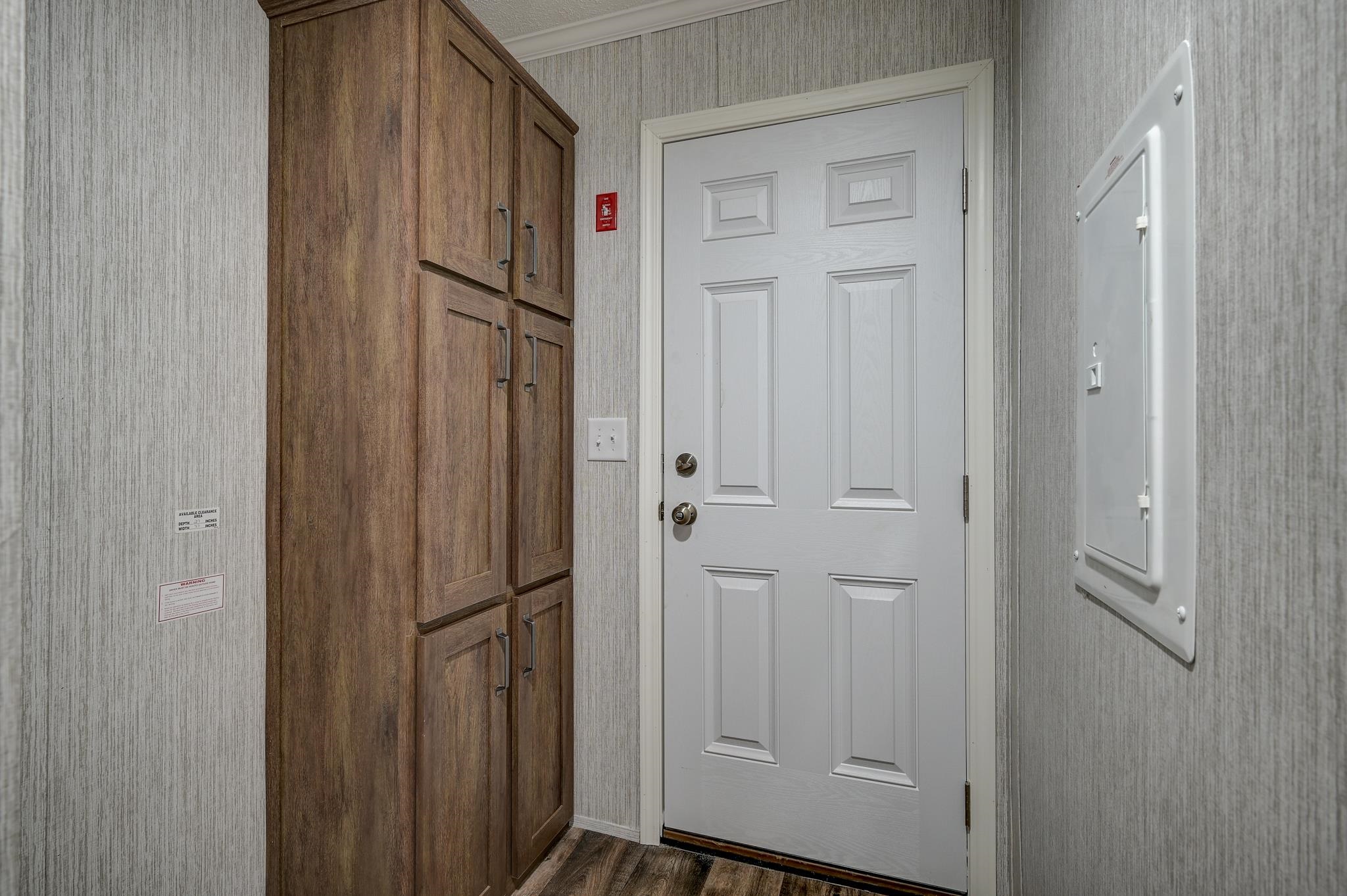 Entryway with a white paneled door beside tall dark wood cabinets.