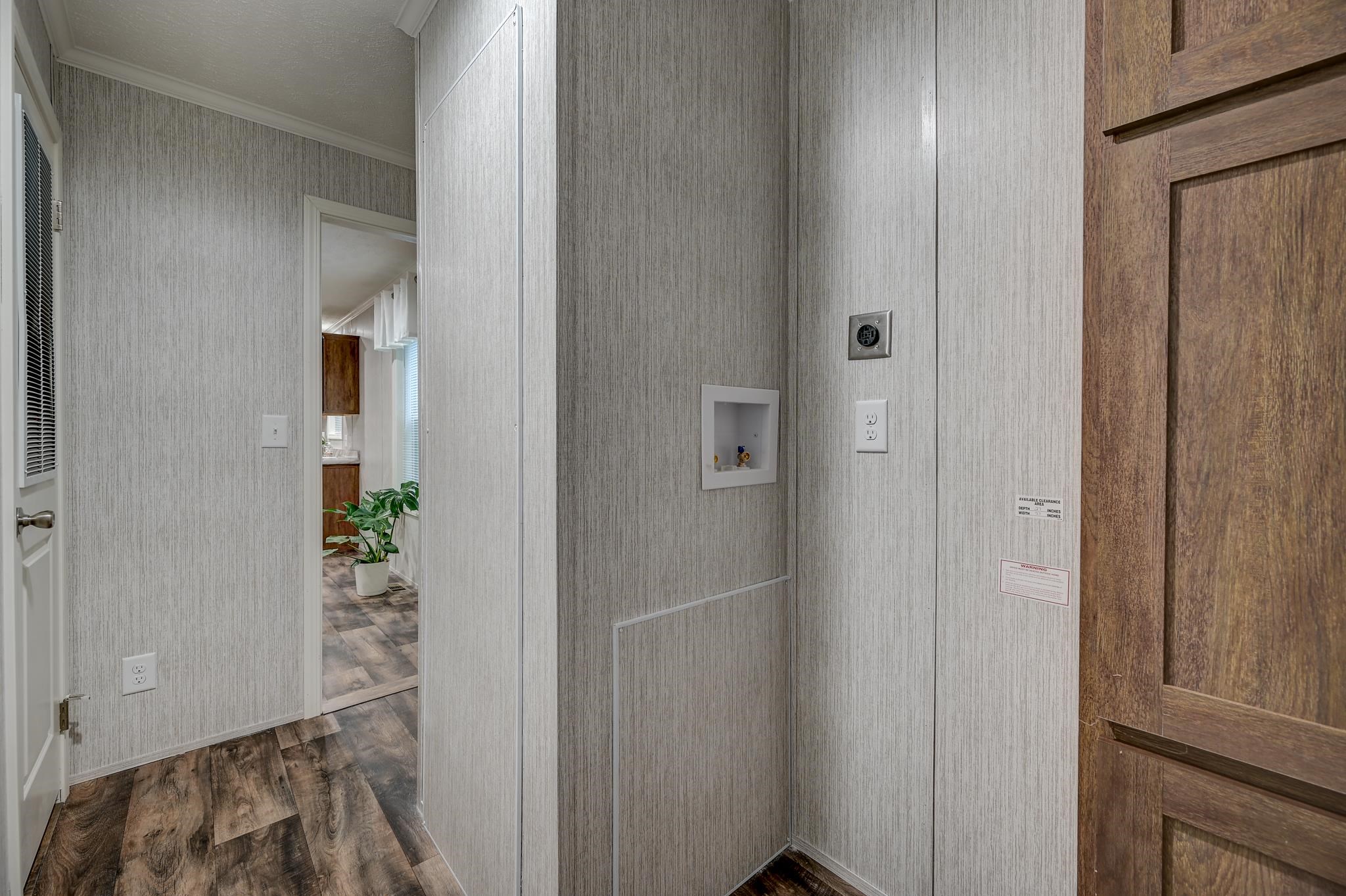 Laundry area with recessed washer and dryer hookups beside a wood-paneled door.