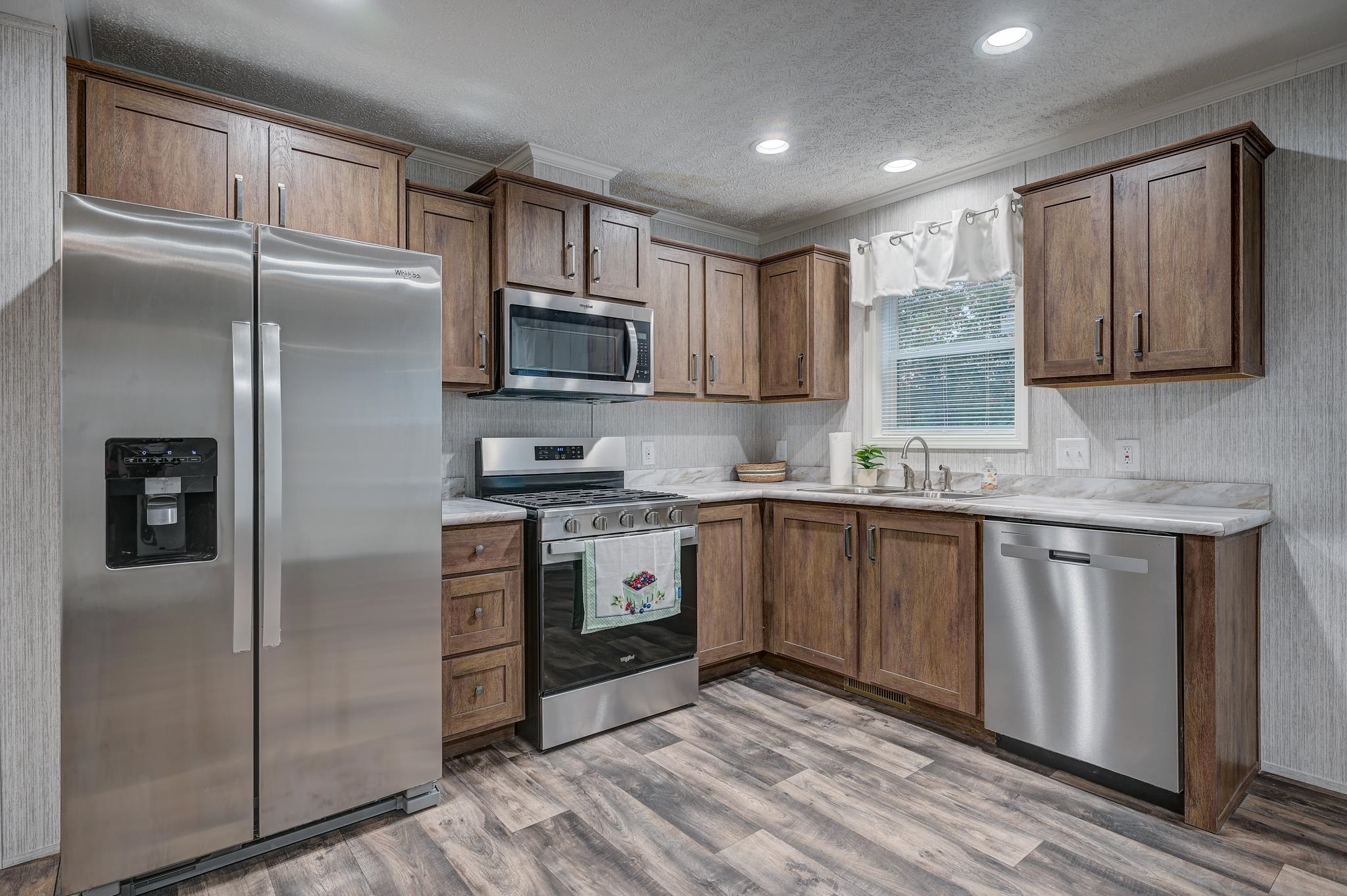 Kitchen with wood cabinets, stainless steel appliances, and a window above the sink.