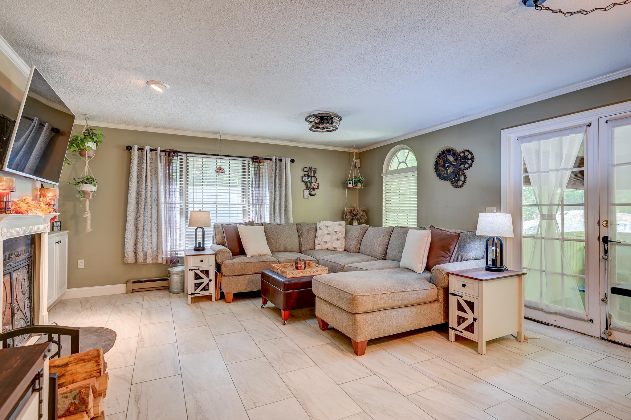 Living room with a gray sectional sofa, tiled floors, fireplace, and glass doors to the patio.