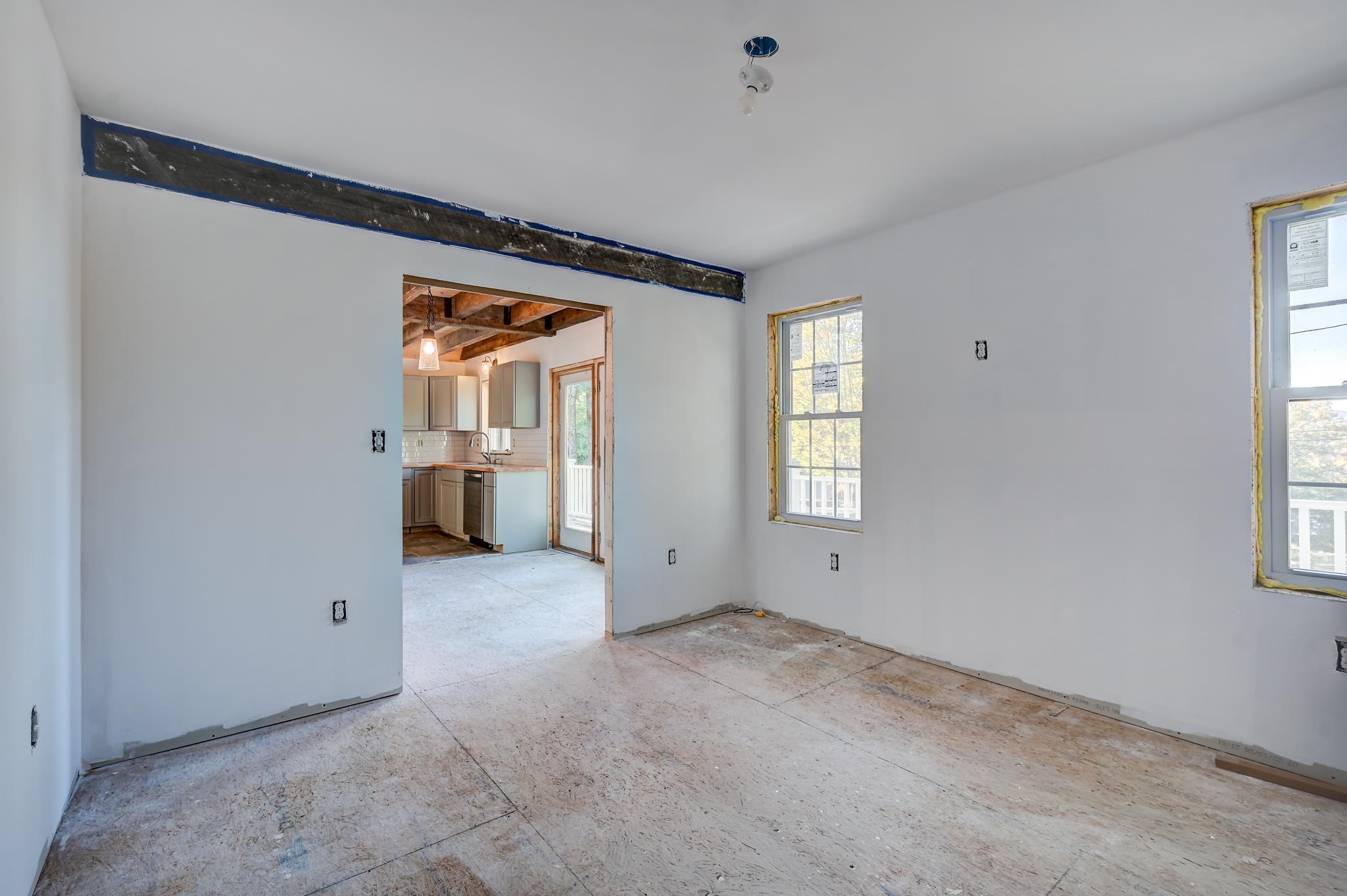Unfinished room with bare subfloor and an open doorway to the kitchen