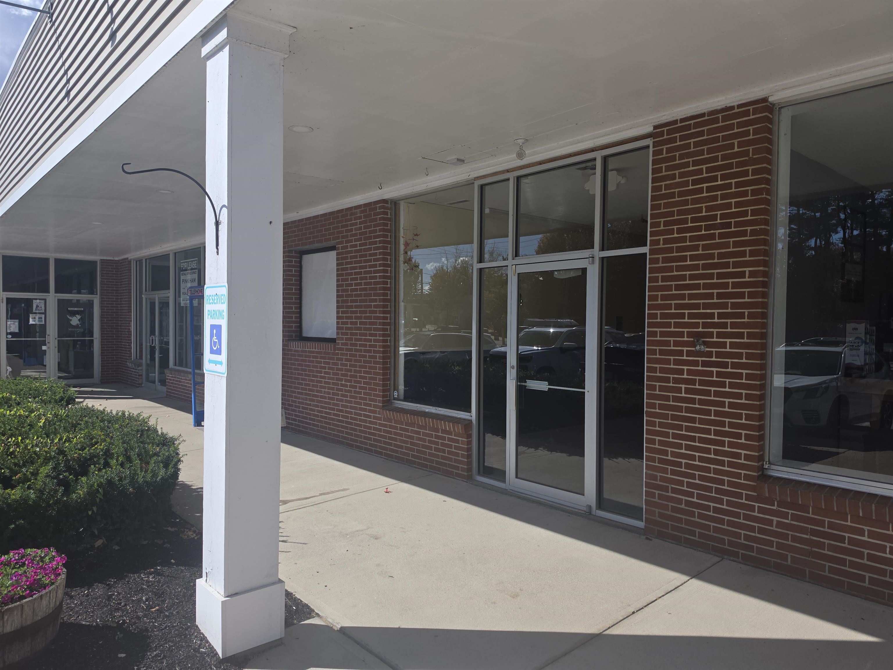 Commercial storefront with red brick walls, large glass windows, and a covered sidewalk.