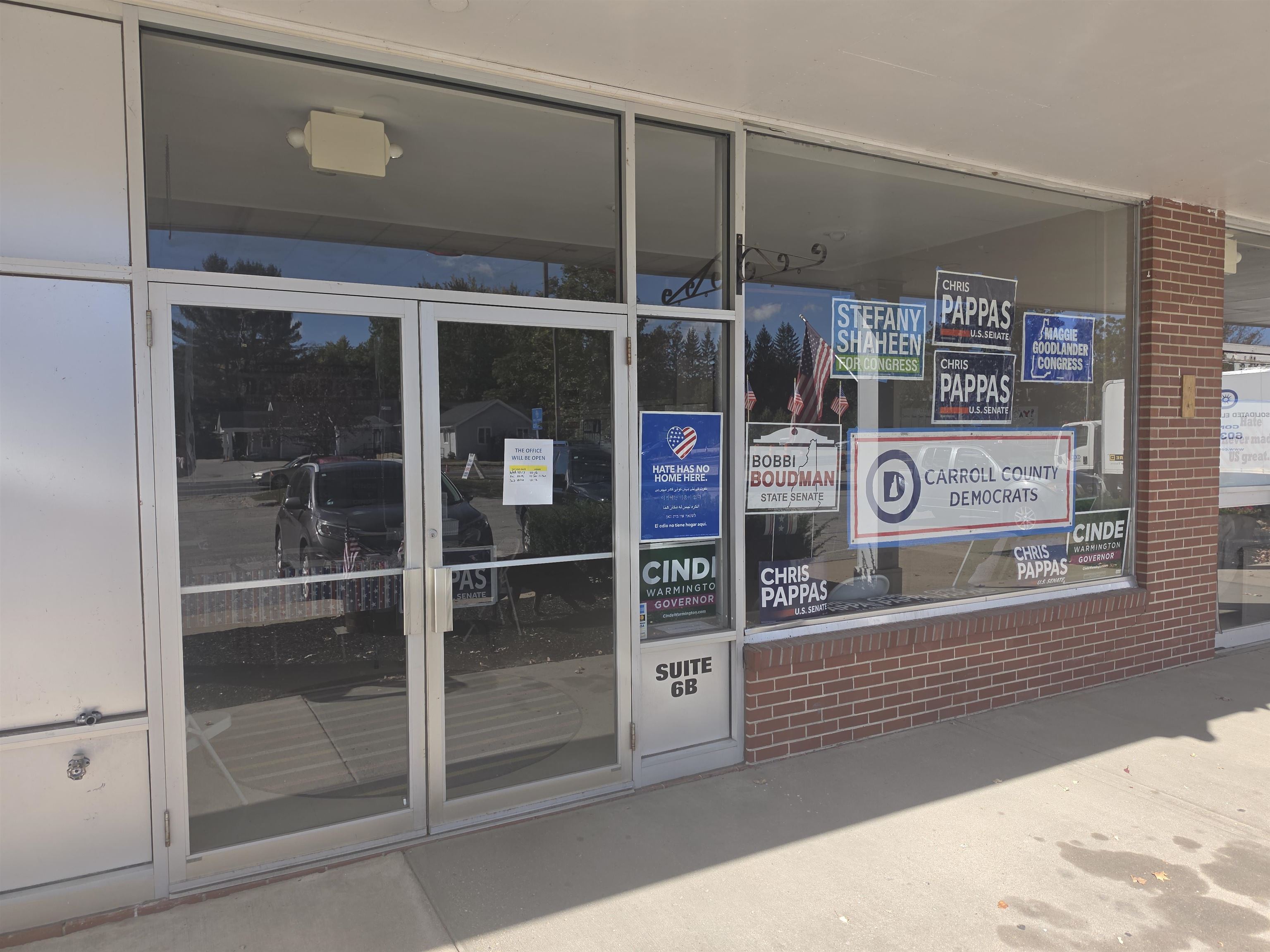 Commercial storefront with glass doors, brick facade, and political campaign signs in the windows.
