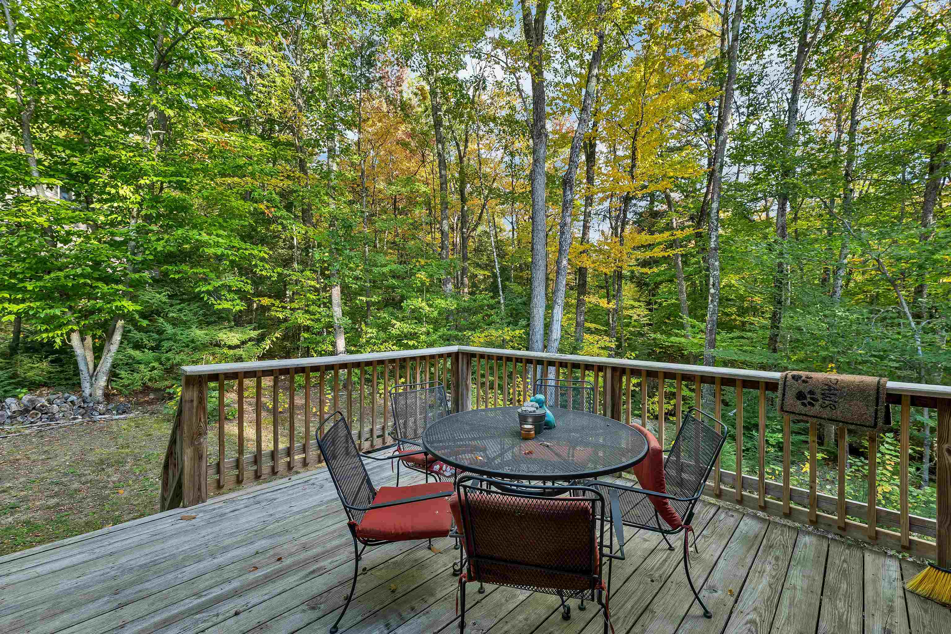 Wooden deck with outdoor dining set overlooking leafy woodland.