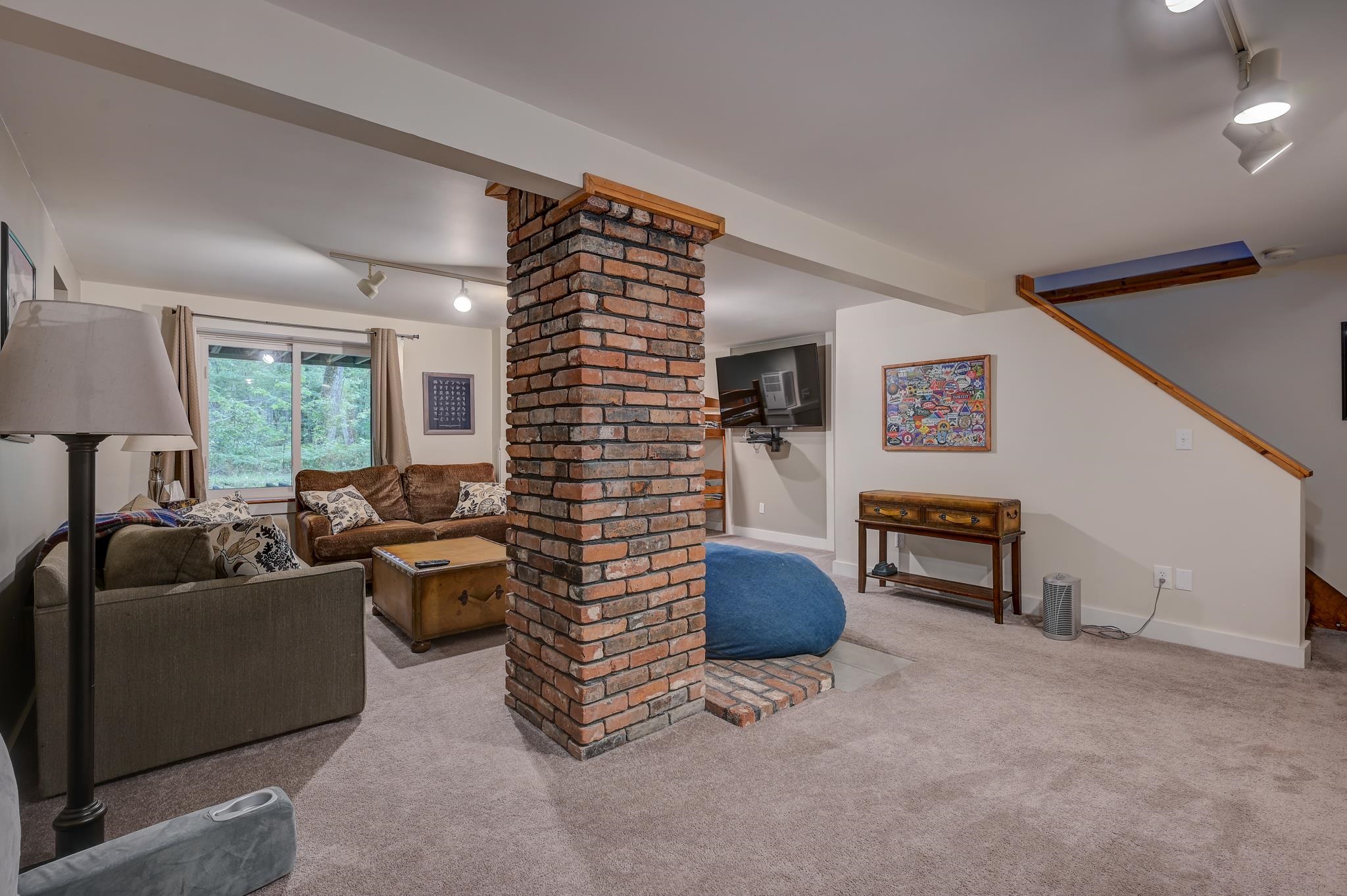 Living room with a central brick column, sofas, and a staircase.