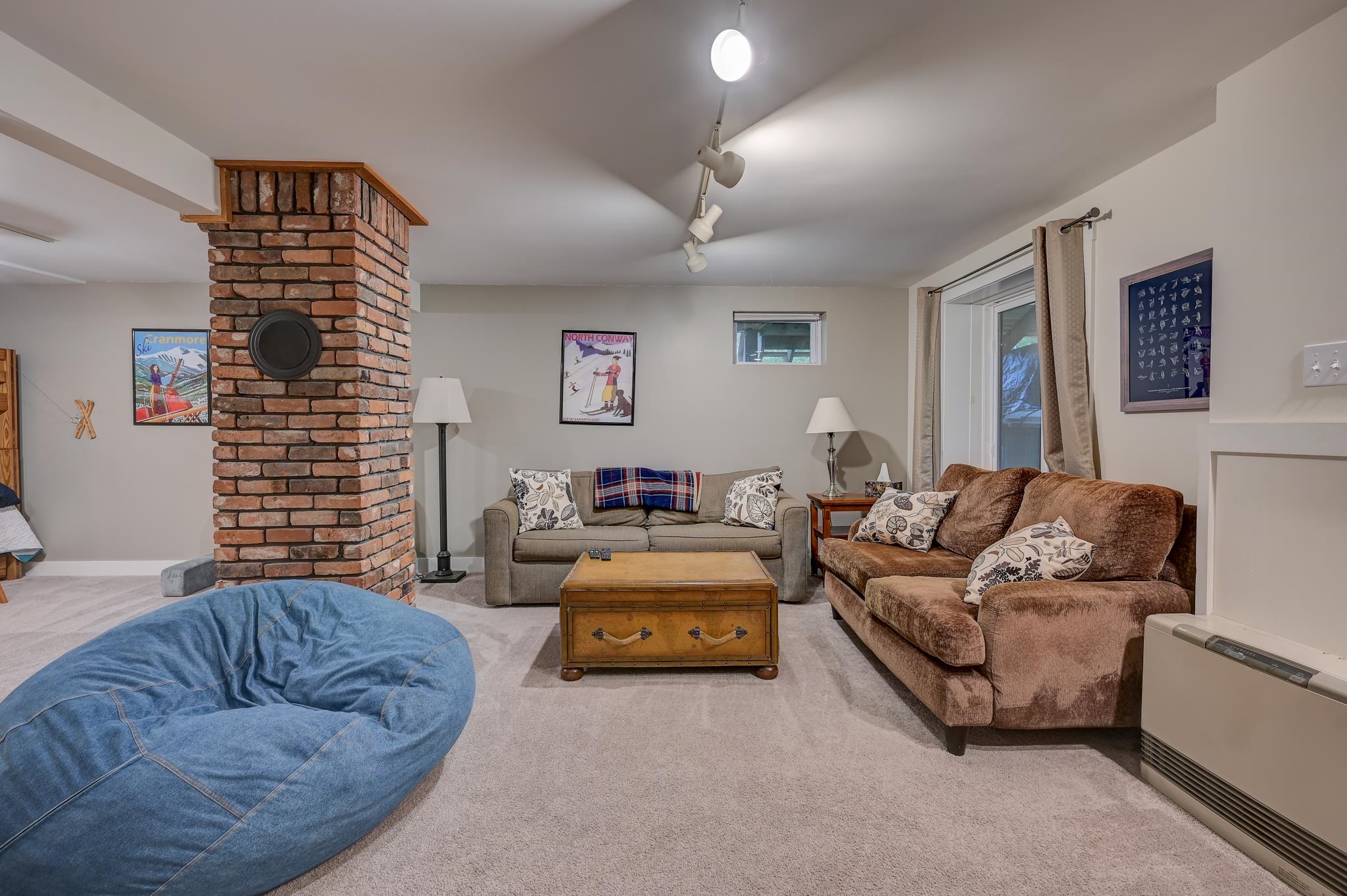 Living room with a brick chimney, two sofas, and a blue beanbag chair.