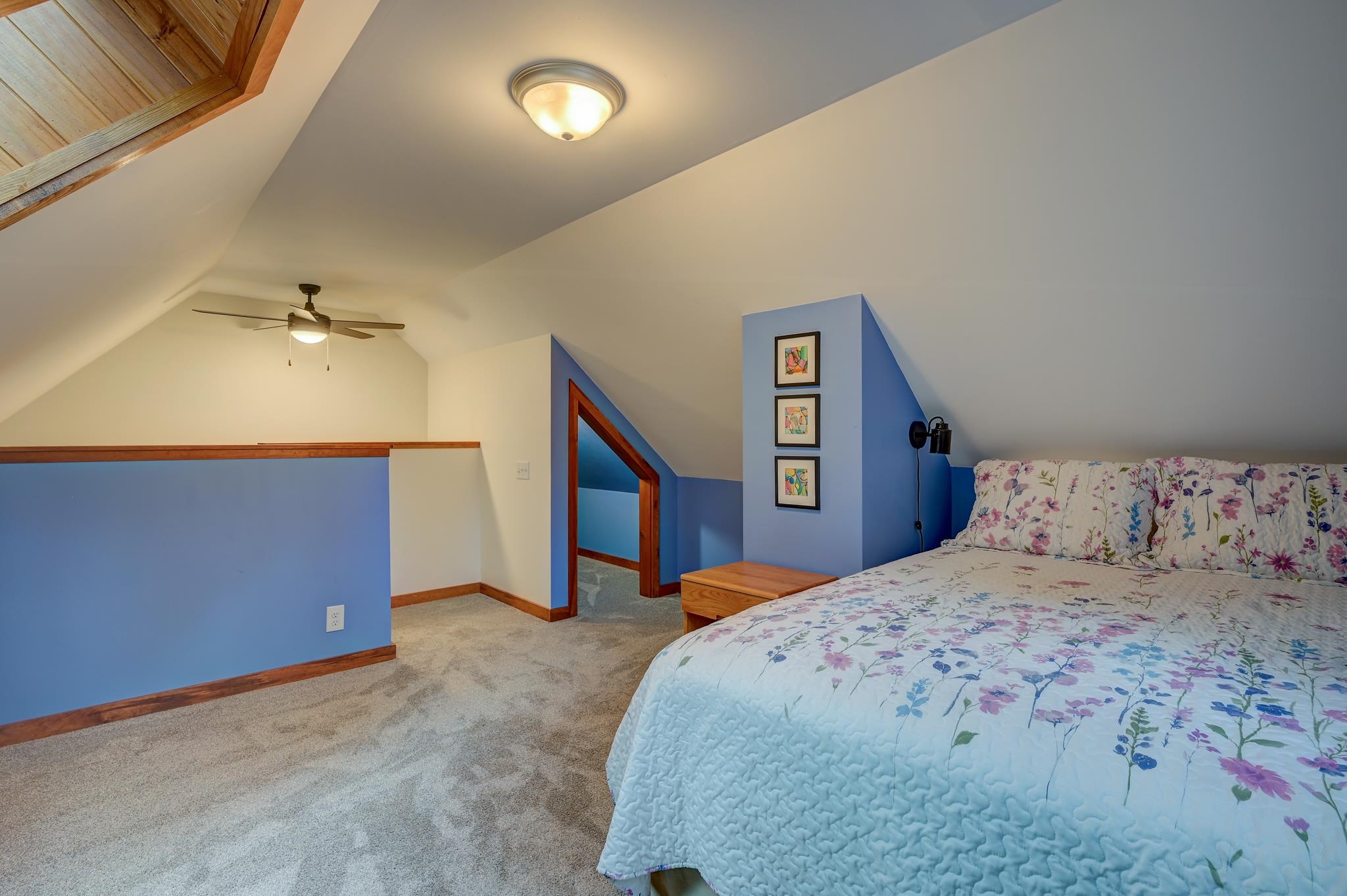 Attic bedroom with a floral-covered bed, blue walls, and sloped ceiling.