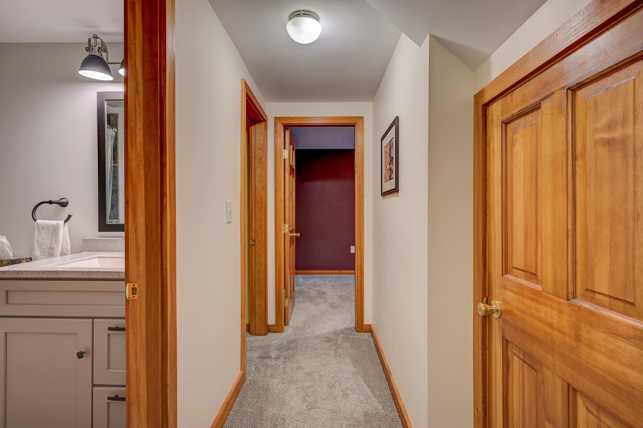 Carpeted hallway with wood-trimmed doors and a bathroom vanity visible on the left.