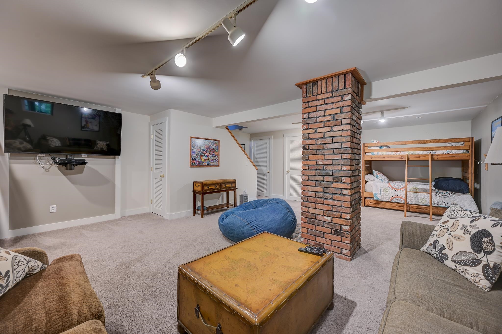 Furnished family room with a brick column, wall-mounted TV, and wooden bunk beds.