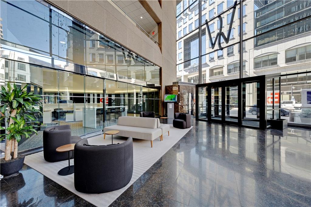 Modern lobby with lounge seating, floor-to-ceiling glass walls, and polished stone floors.