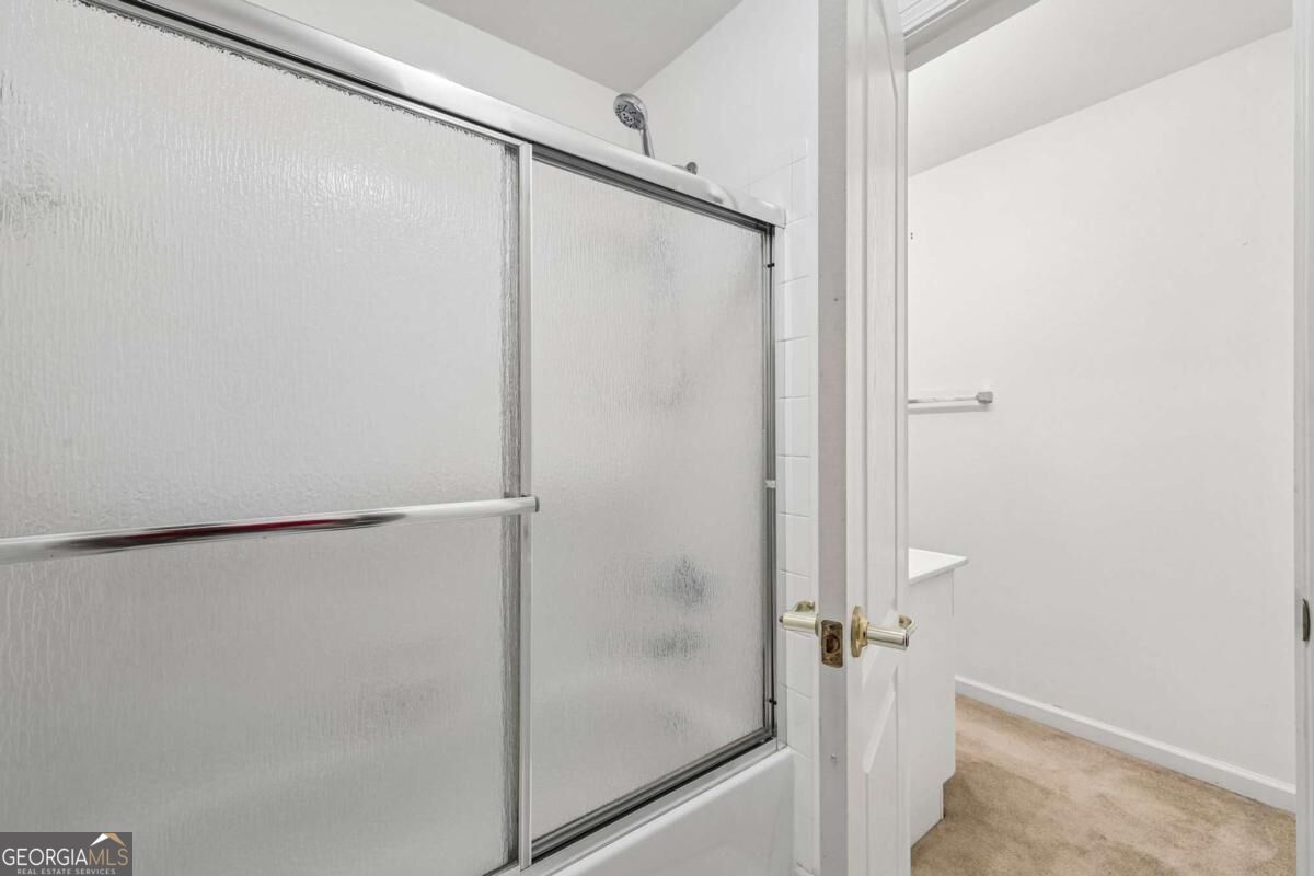 Frosted-glass sliding shower door beside an open doorway to a carpeted room.
