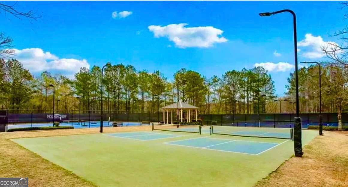 Community tennis courts with blue and green surfaces, tall fencing, and a pavilion.